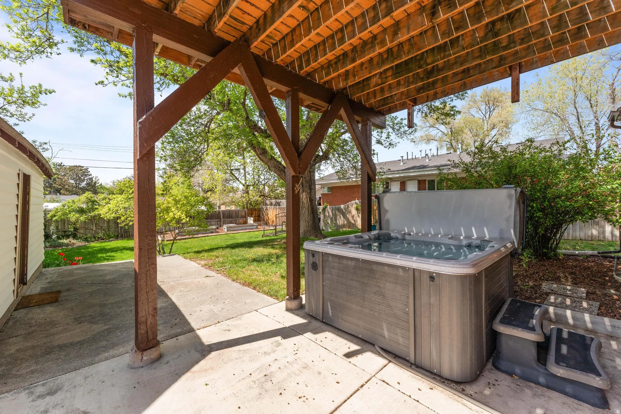 Fenced backyard featuring a patio area and a hot tub