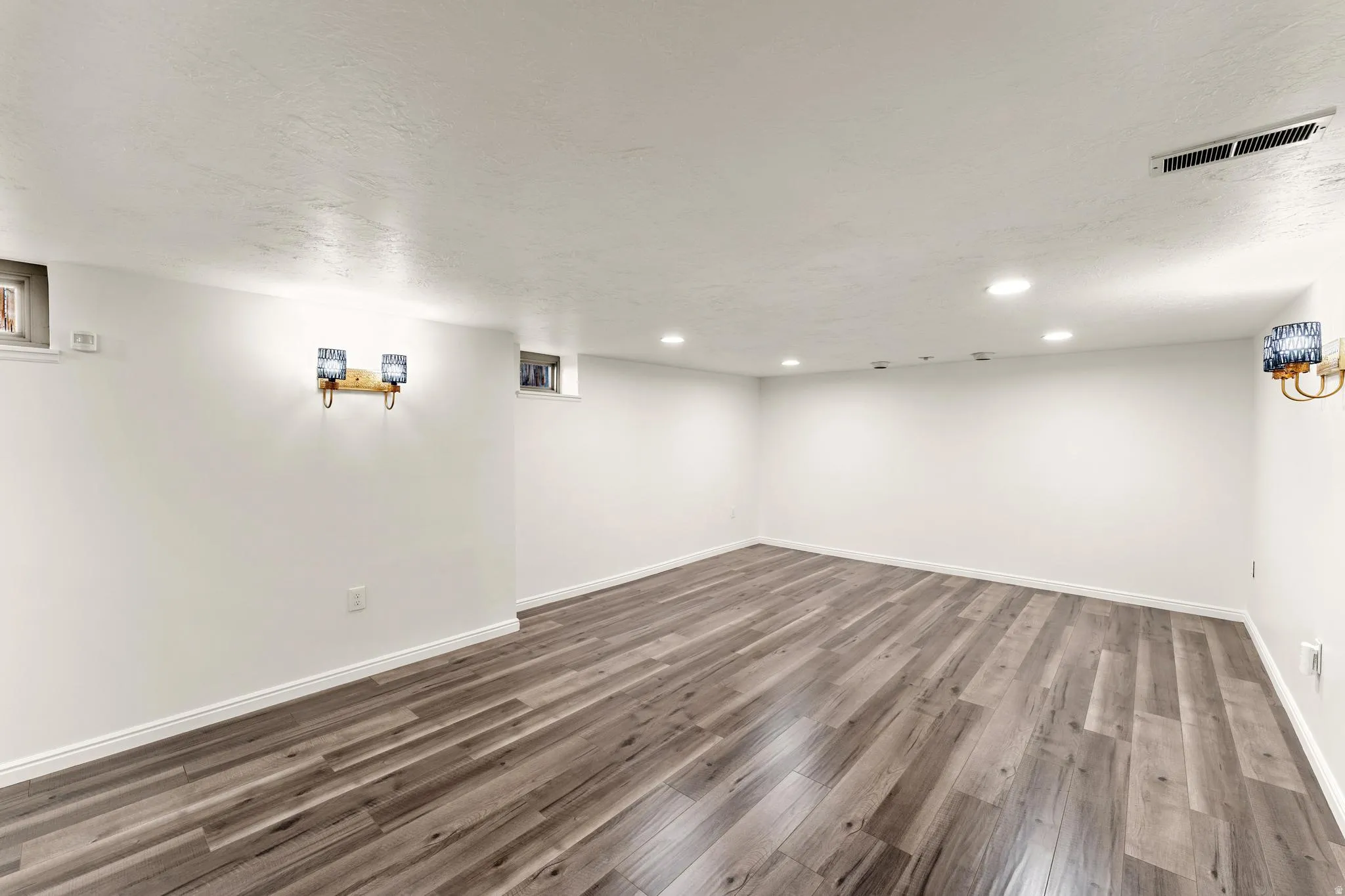 Finished below grade area featuring dark wood finished floors, a textured ceiling, and recessed lighting