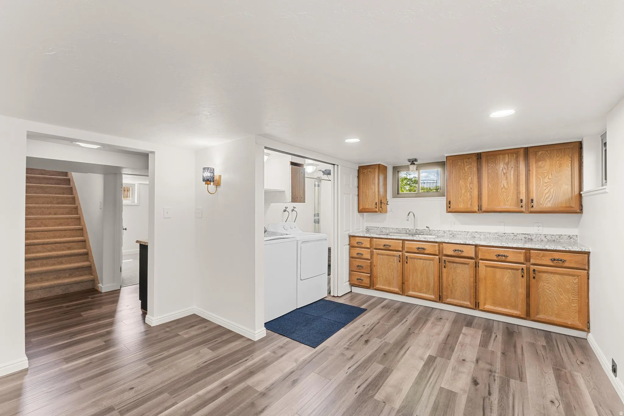 Kitchen with light countertops, light wood finished floors, separate washer and dryer, wood finish cabinetry, and recessed lighting