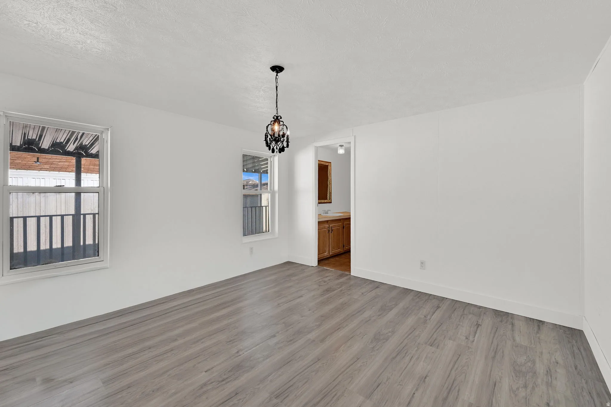 Unfurnished dining area featuring light wood-style flooring, suspended lighting, and a textured ceiling