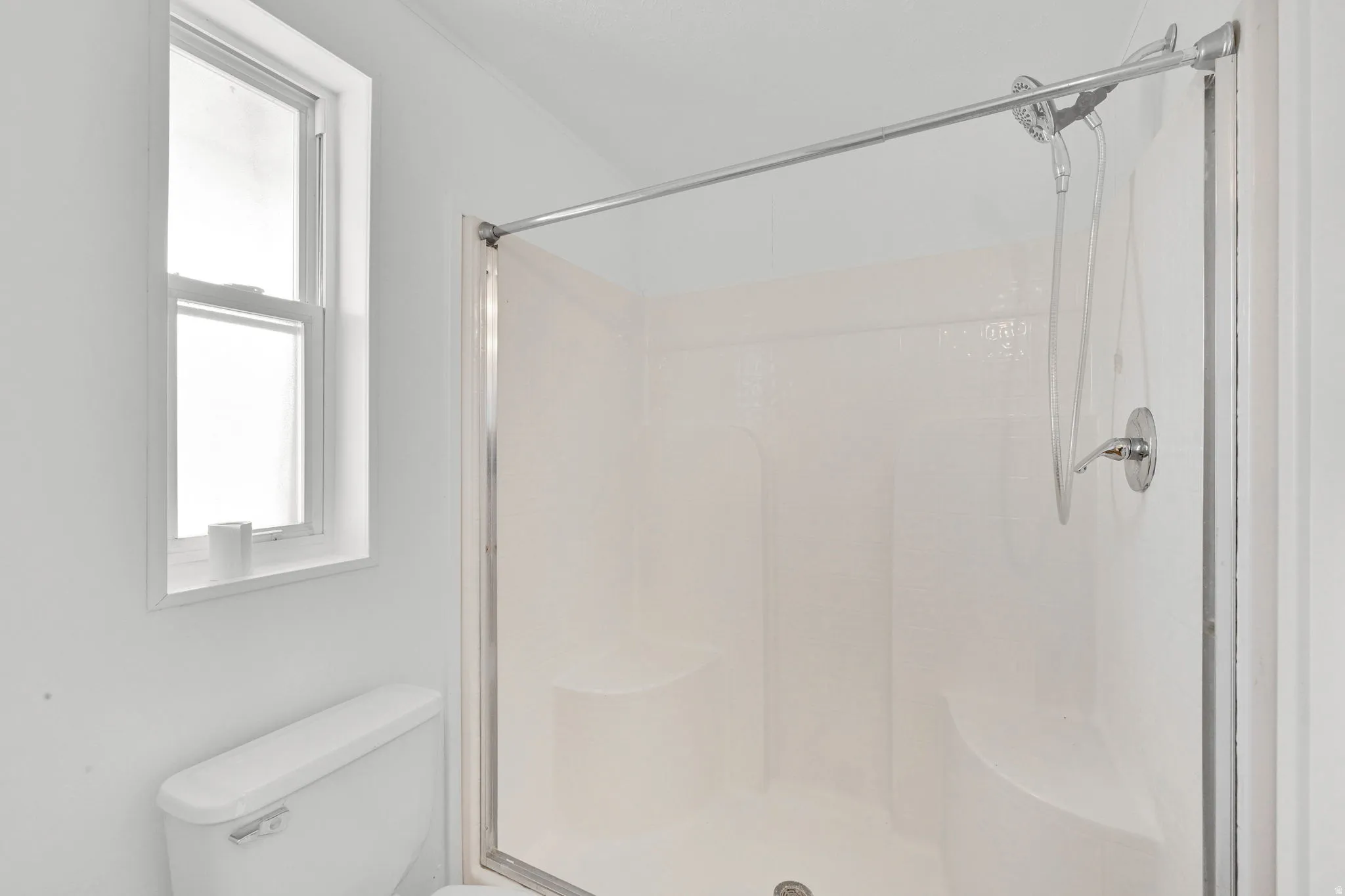 Full bath featuring a shower stall and toilet