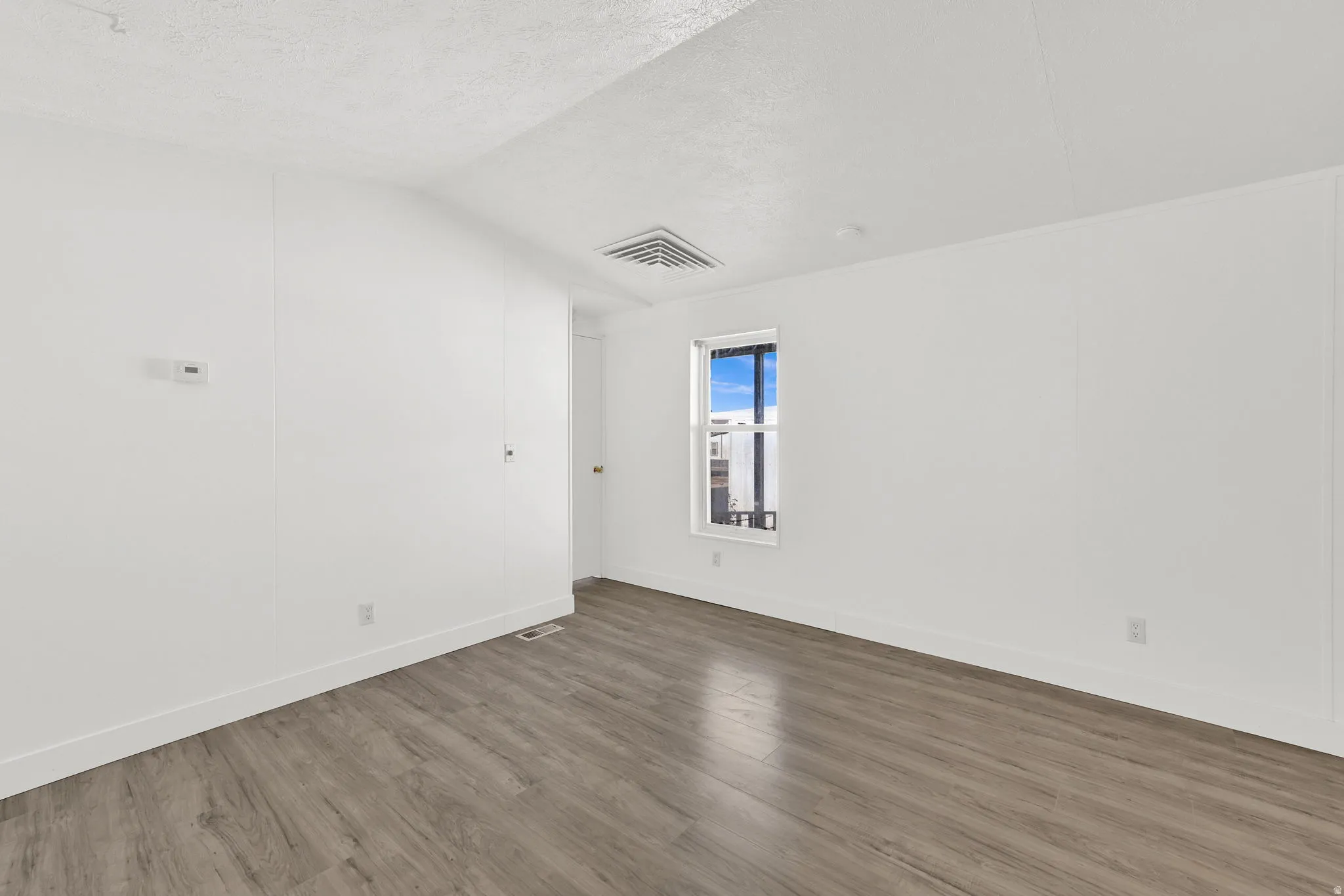 Empty room featuring dark wood finished floors and baseboards