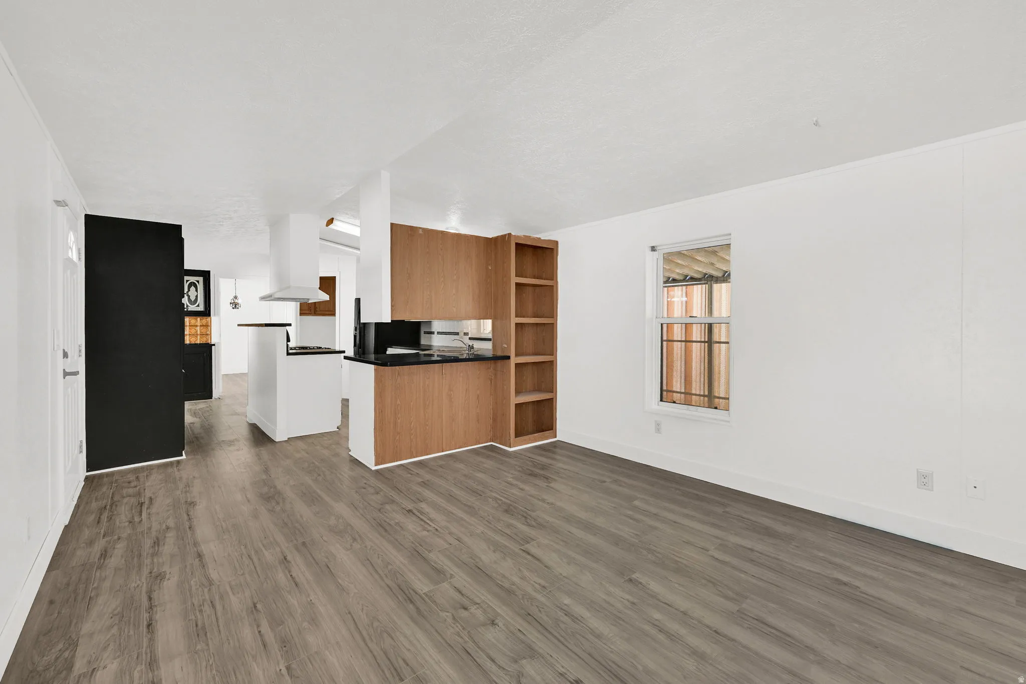 Kitchen with dark countertops, open floor plan, dark wood-style floors, a peninsula, and open shelves
