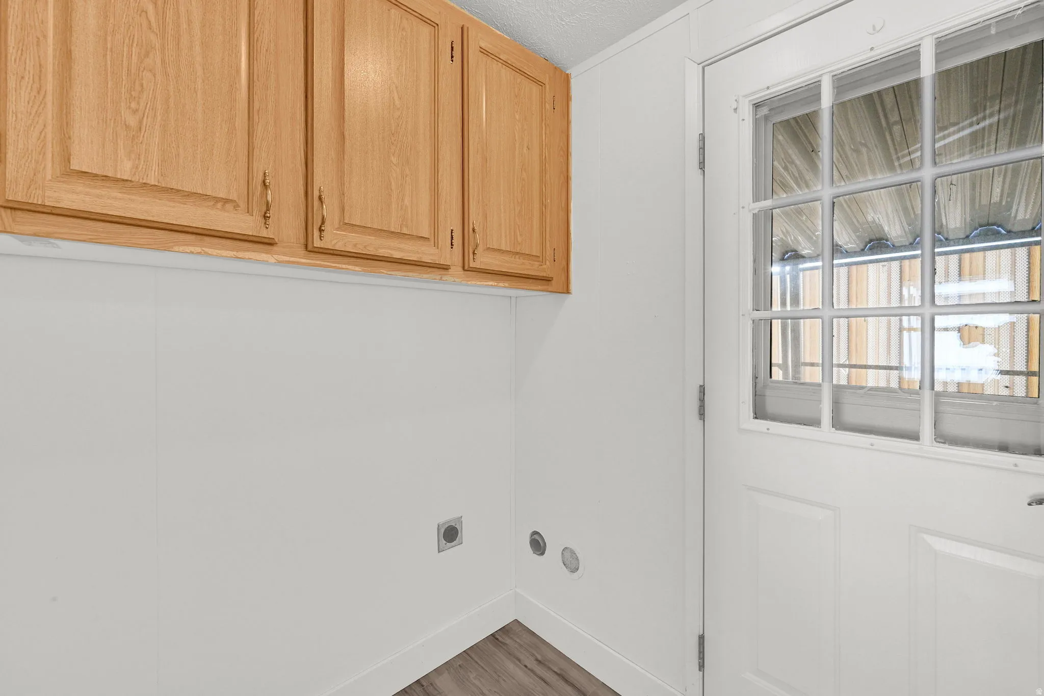 Laundry room featuring cabinet space, dark wood-style flooring, hookup for an electric dryer, and a textured ceiling