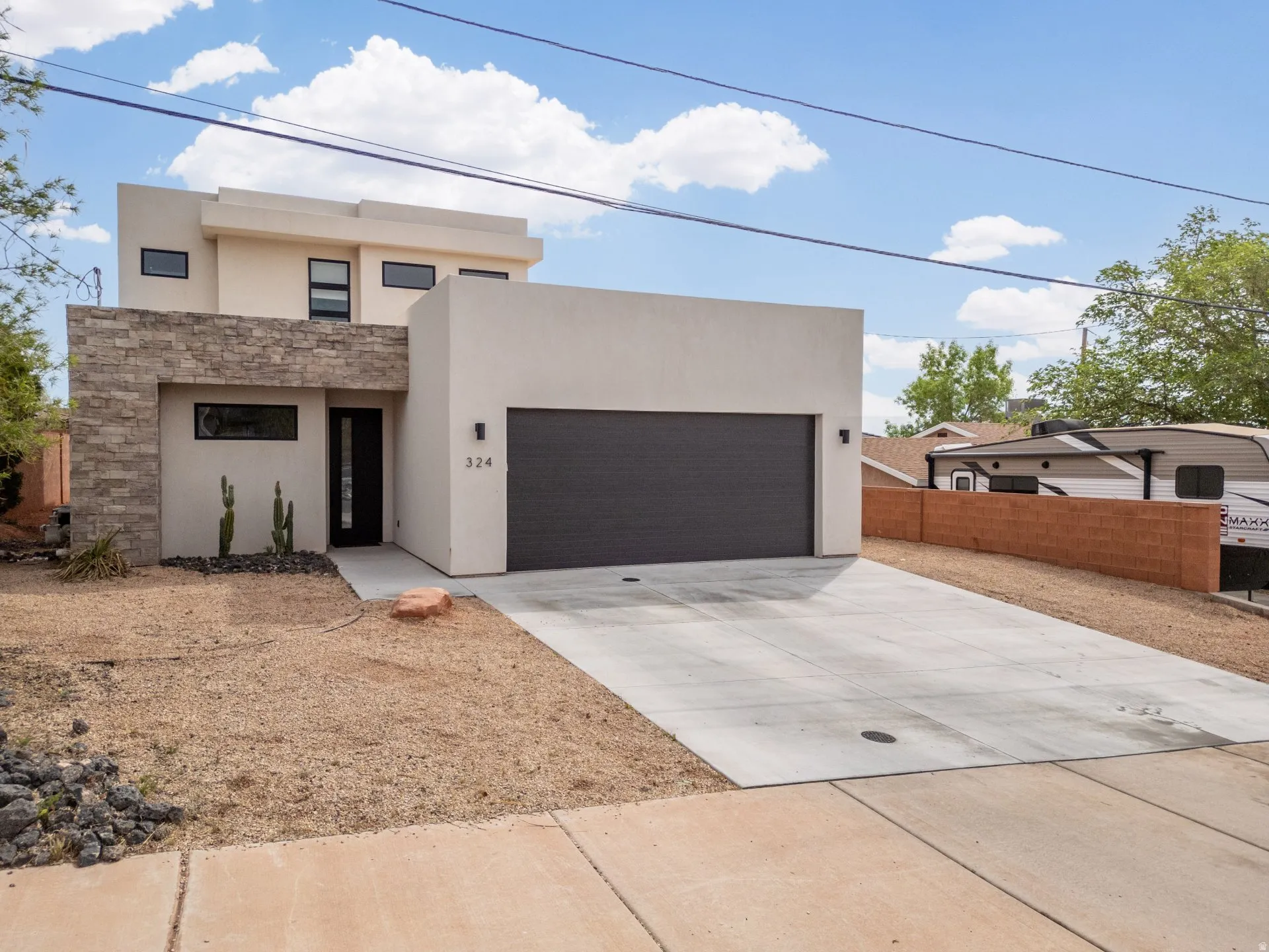 Modern home with concrete driveway, stucco siding, a garage, and stone siding