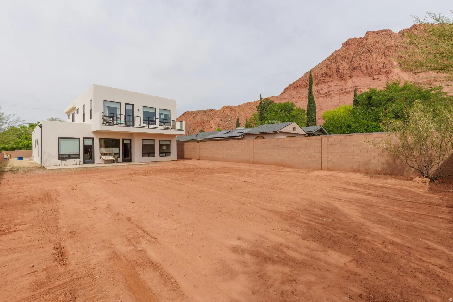 Back of house with stucco siding, a mountain view, a fenced backyard, a balcony, and a patio area