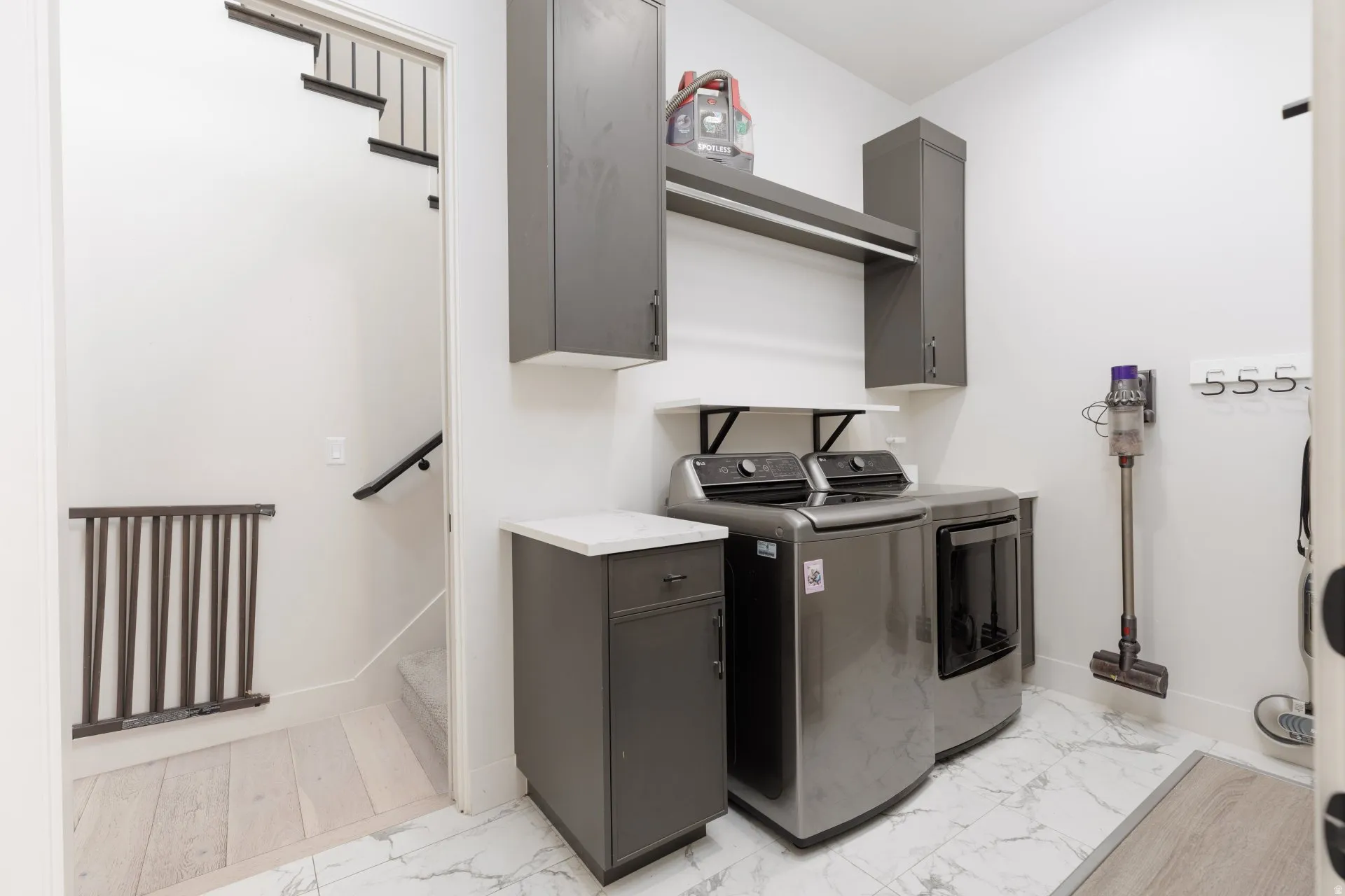 Laundry area with cabinet space, light marble finish flooring, and washer and clothes dryer