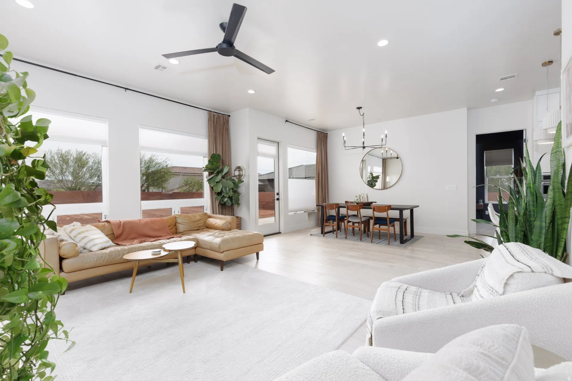 Living room with a ceiling fan, light wood-style floors, and suspended lighting