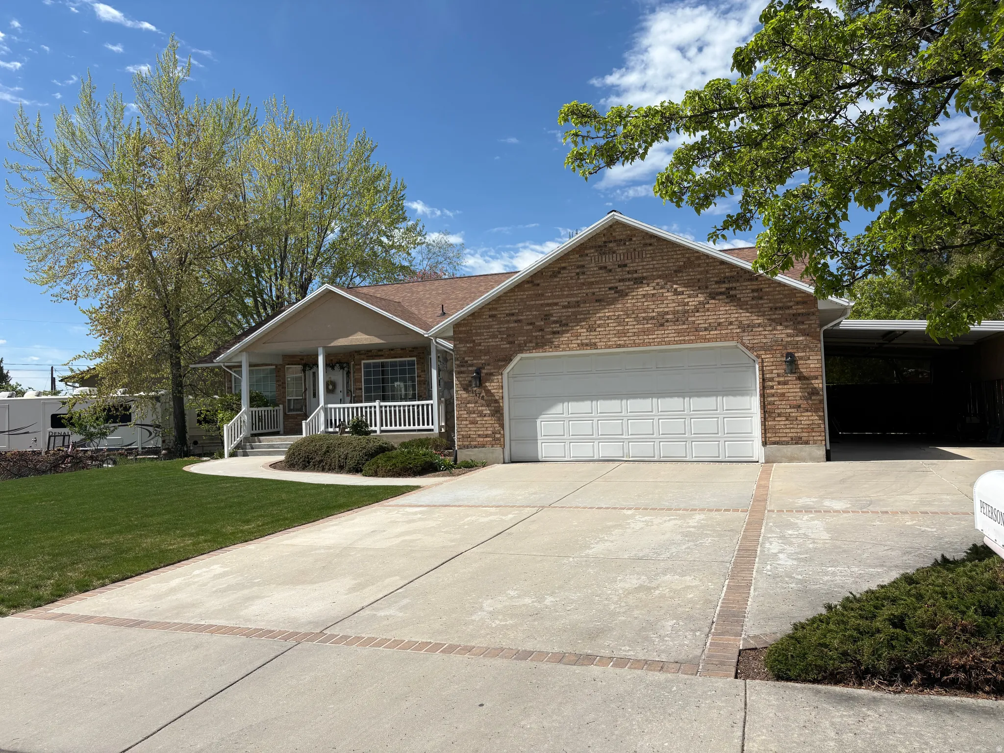 Ranch-style house with covered porch, driveway, a front yard, brick siding, and an attached garage