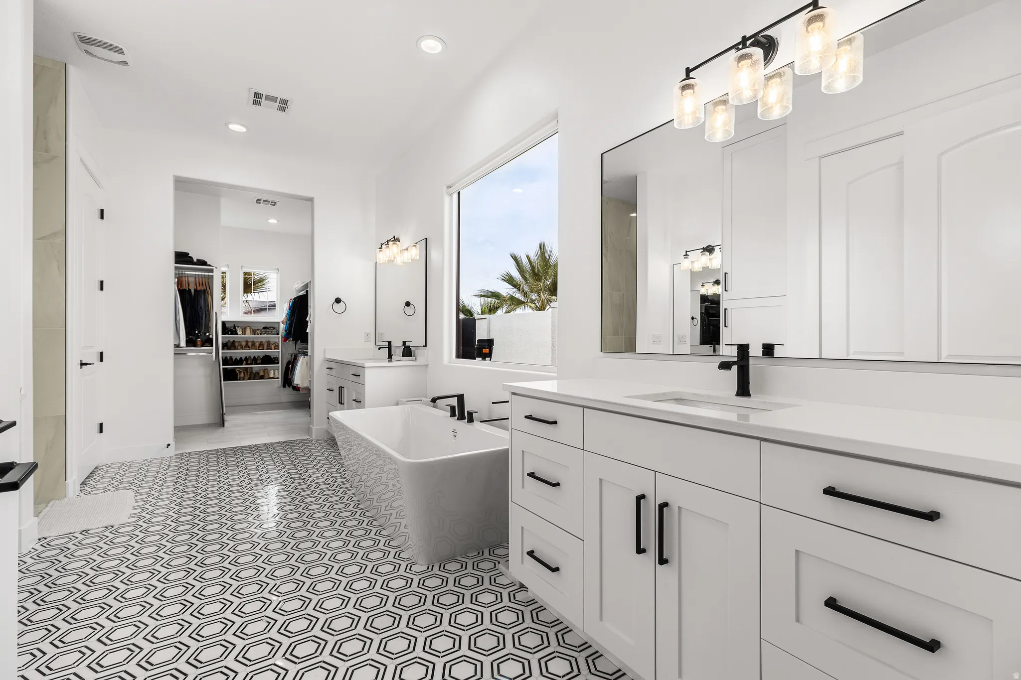 Bathroom with a soaking tub, two vanities, recessed lighting, and a spacious closet