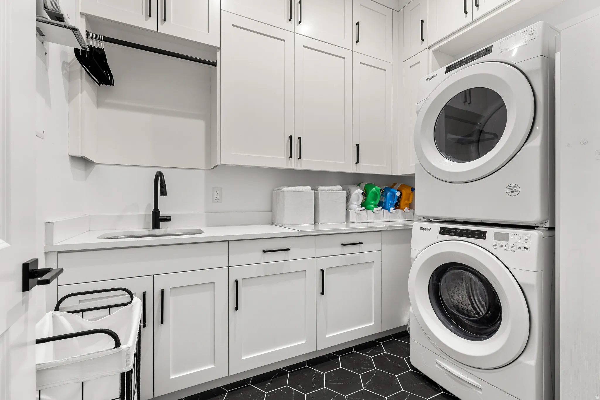 Laundry area featuring cabinet space, stacked washer and clothes dryer, and dark tile patterned floors