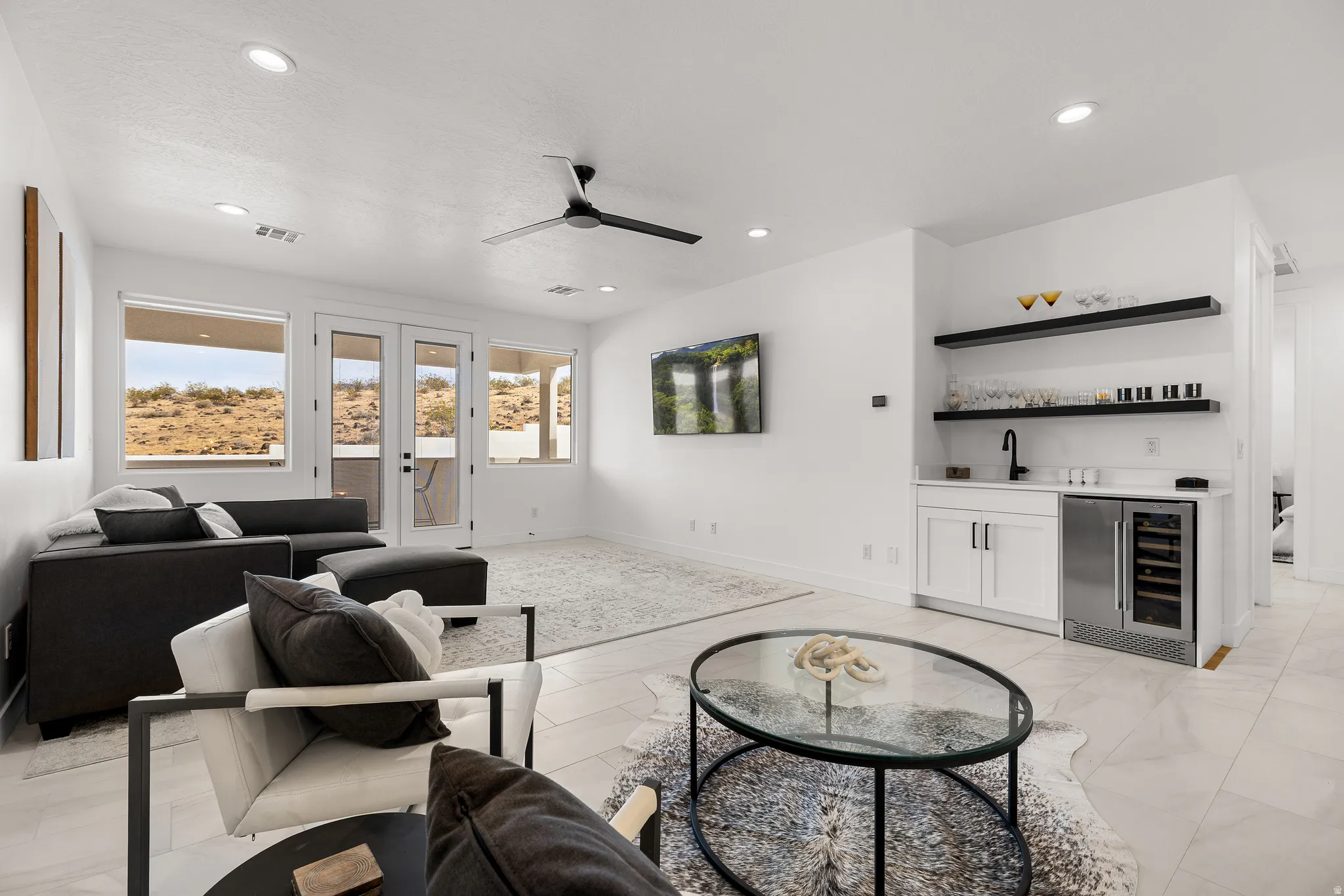 Living area featuring french doors, beverage cooler, bar with sink, ceiling fan, and recessed lighting