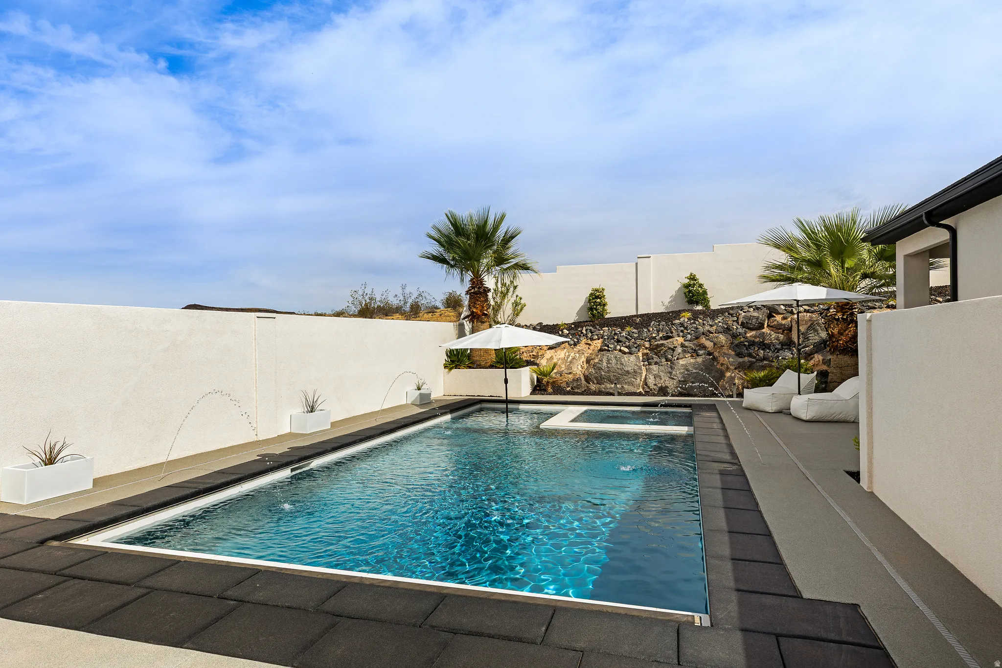 View of swimming pool with a fenced backyard, patio surround, and an in-ground hot tub