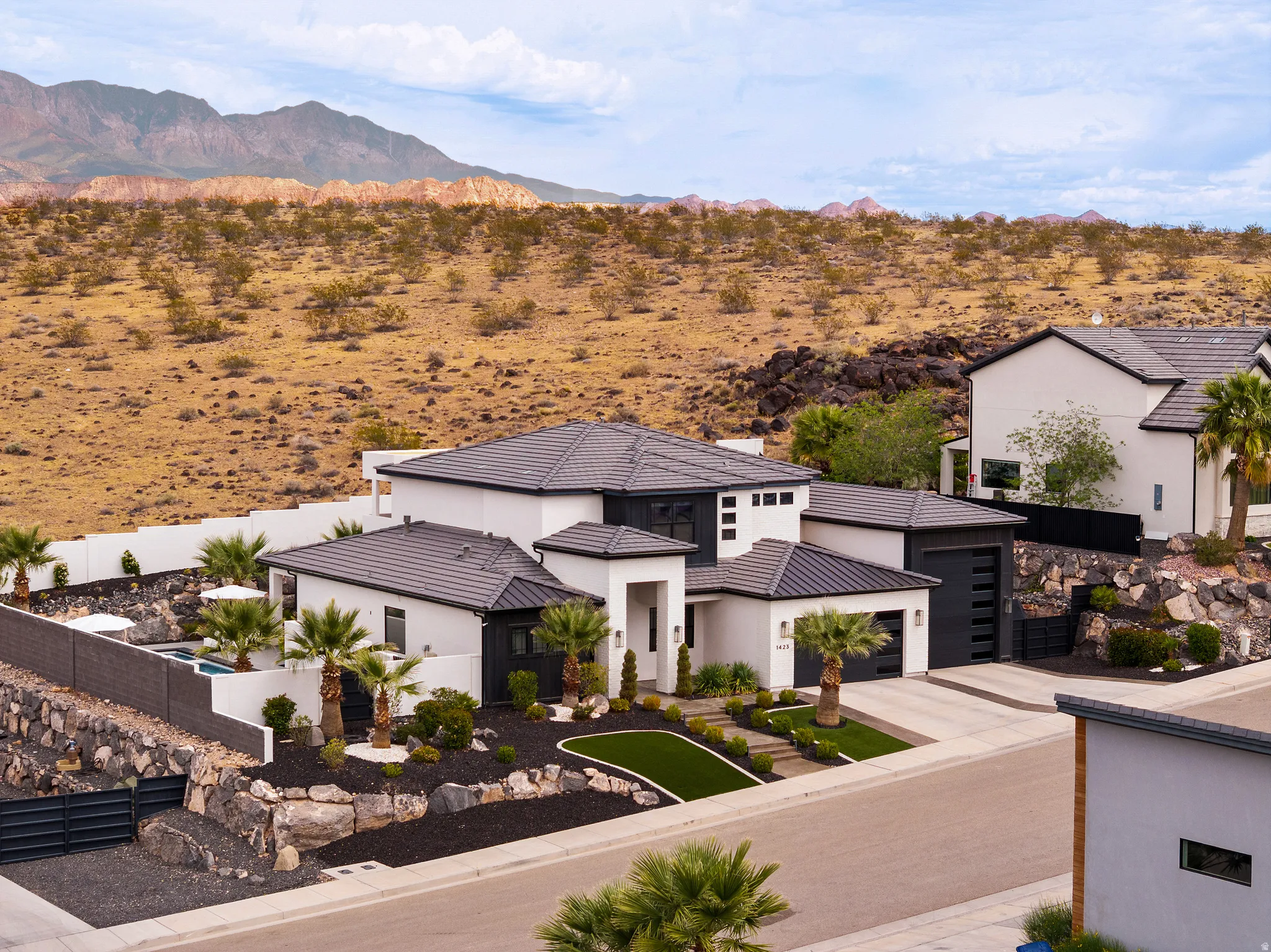 View of front of house featuring a mountain view, concrete driveway, stucco siding, a garage, and view of desert landscape