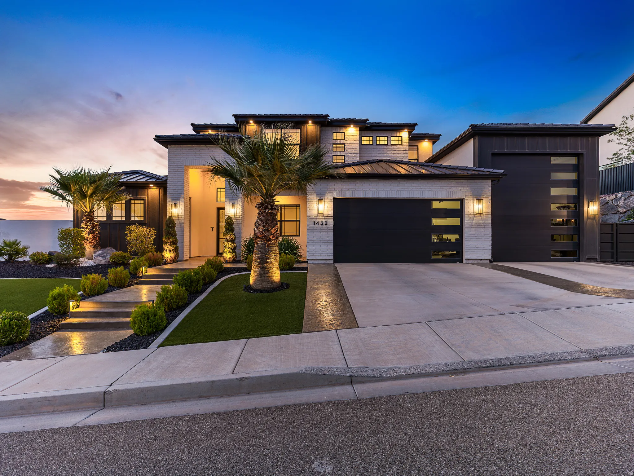 View of front of house featuring driveway, an attached garage, a standing seam roof, a front lawn, and brick siding
