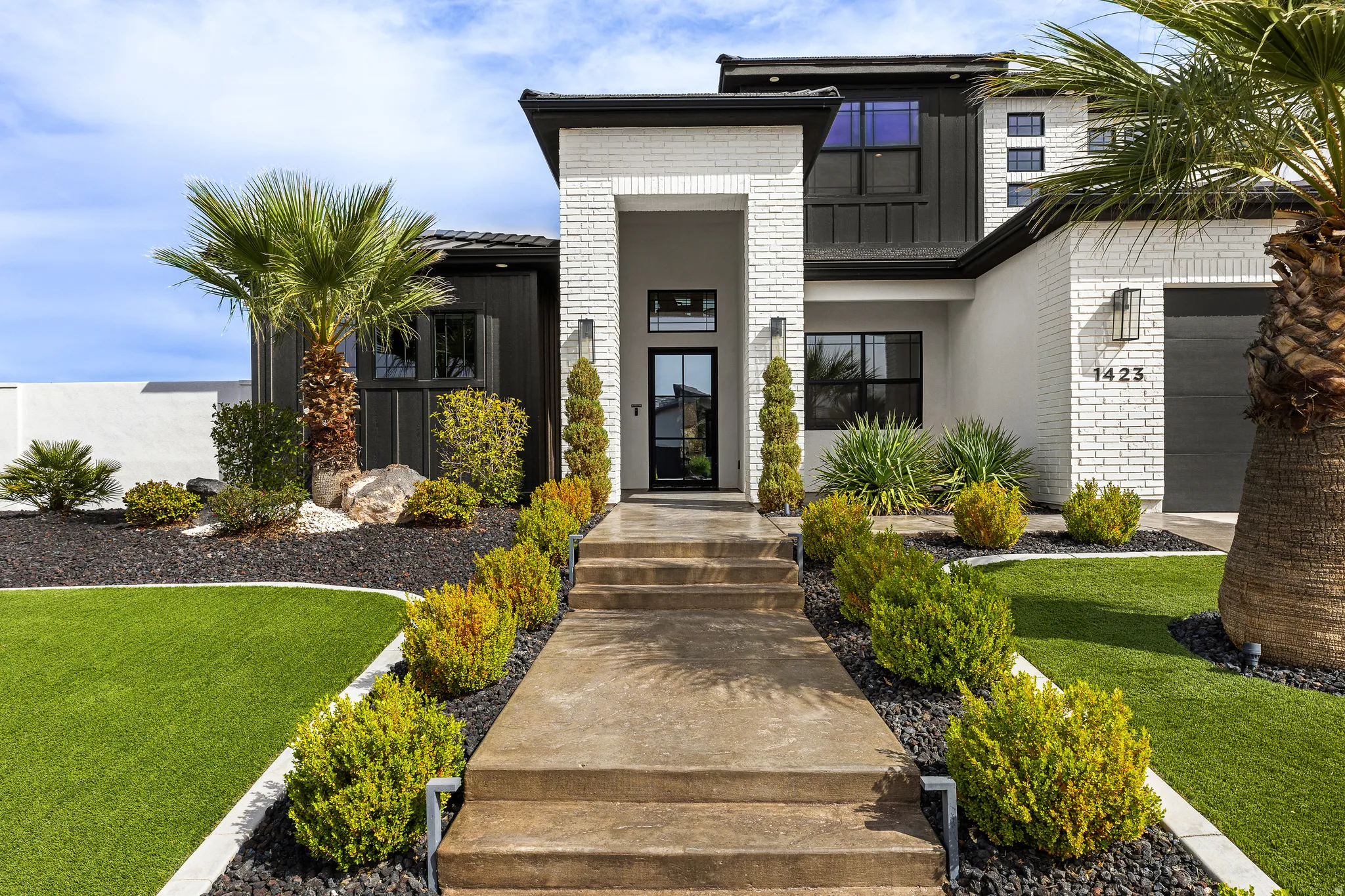 View of exterior entry with brick siding, a lawn, and stucco siding