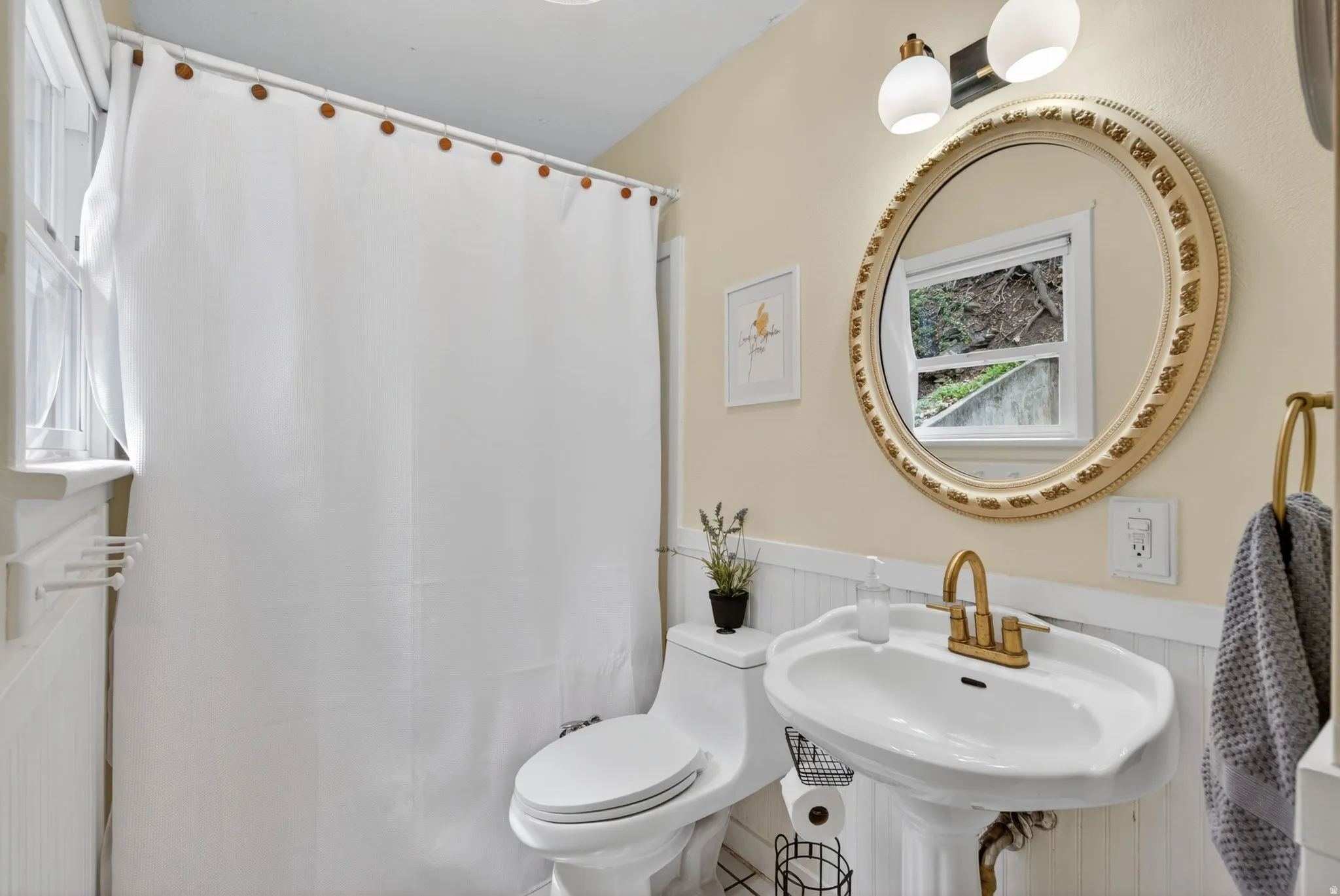Full bath featuring a wainscoted wall and curtained shower
