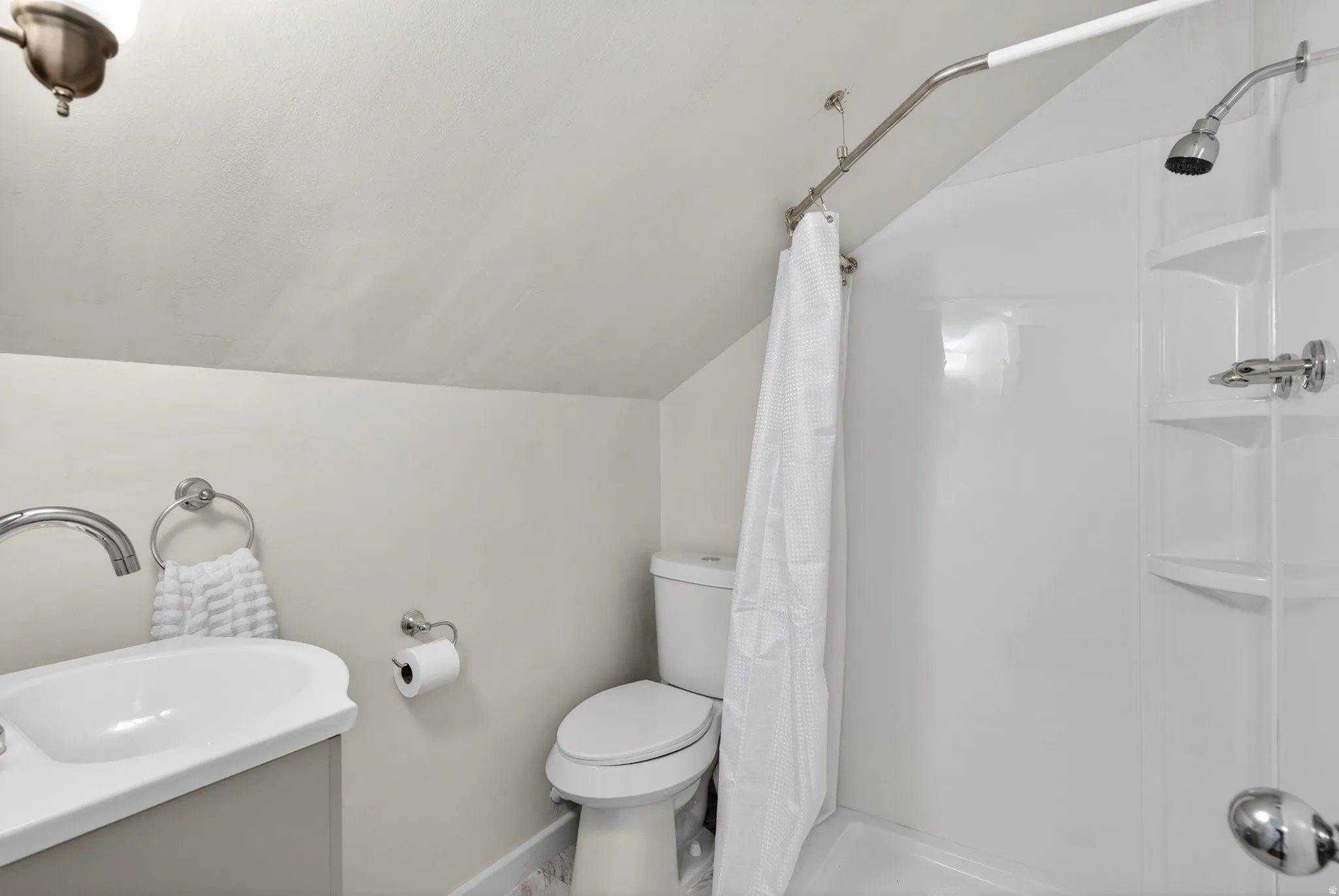 Full bathroom with vaulted ceiling, a shower stall, and vanity