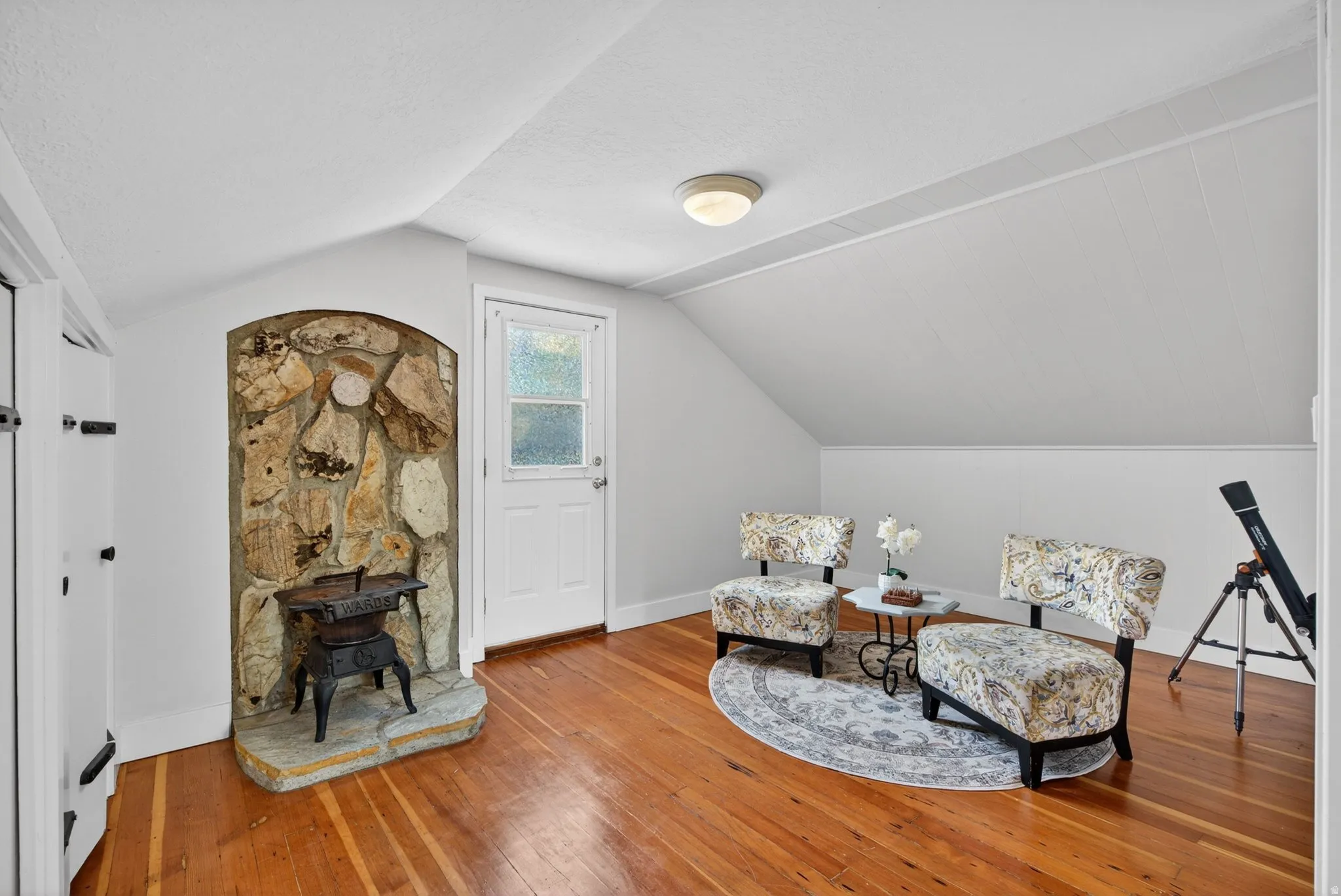 Sitting room featuring hardwood / wood-style flooring, a wood stove, and a textured ceiling