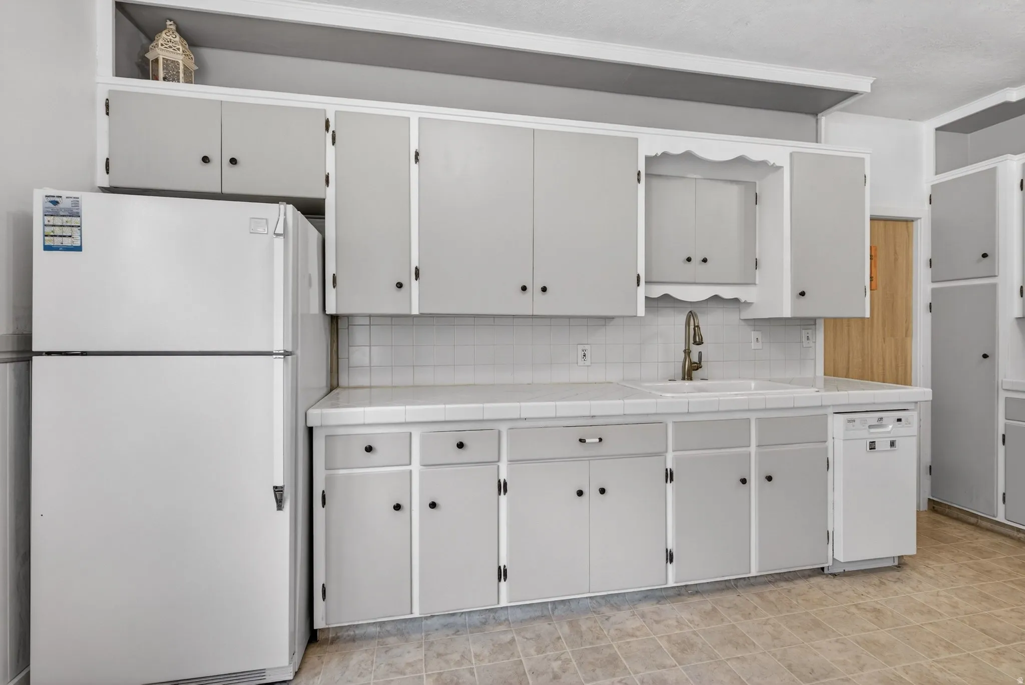 Kitchen featuring tile counters, white appliances, white cabinets, and backsplash