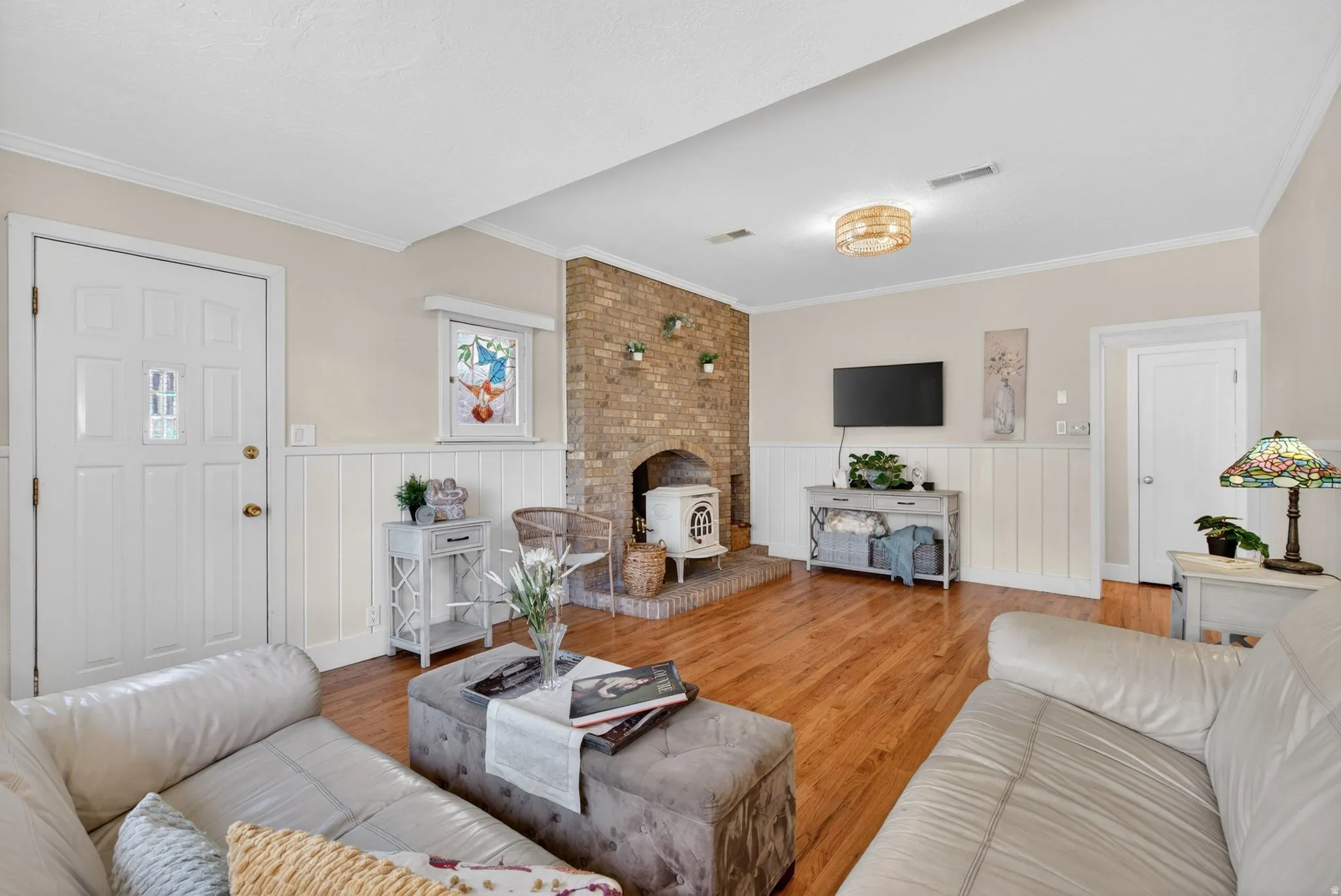 Living room featuring light wood finished floors, ornamental molding, and a wainscoted wall