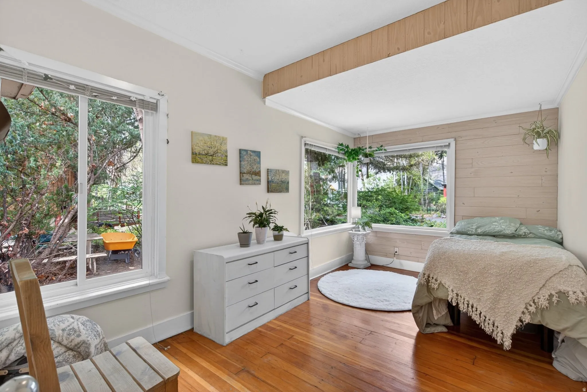 Bedroom featuring crown molding, light wood-style floors, and wooden walls