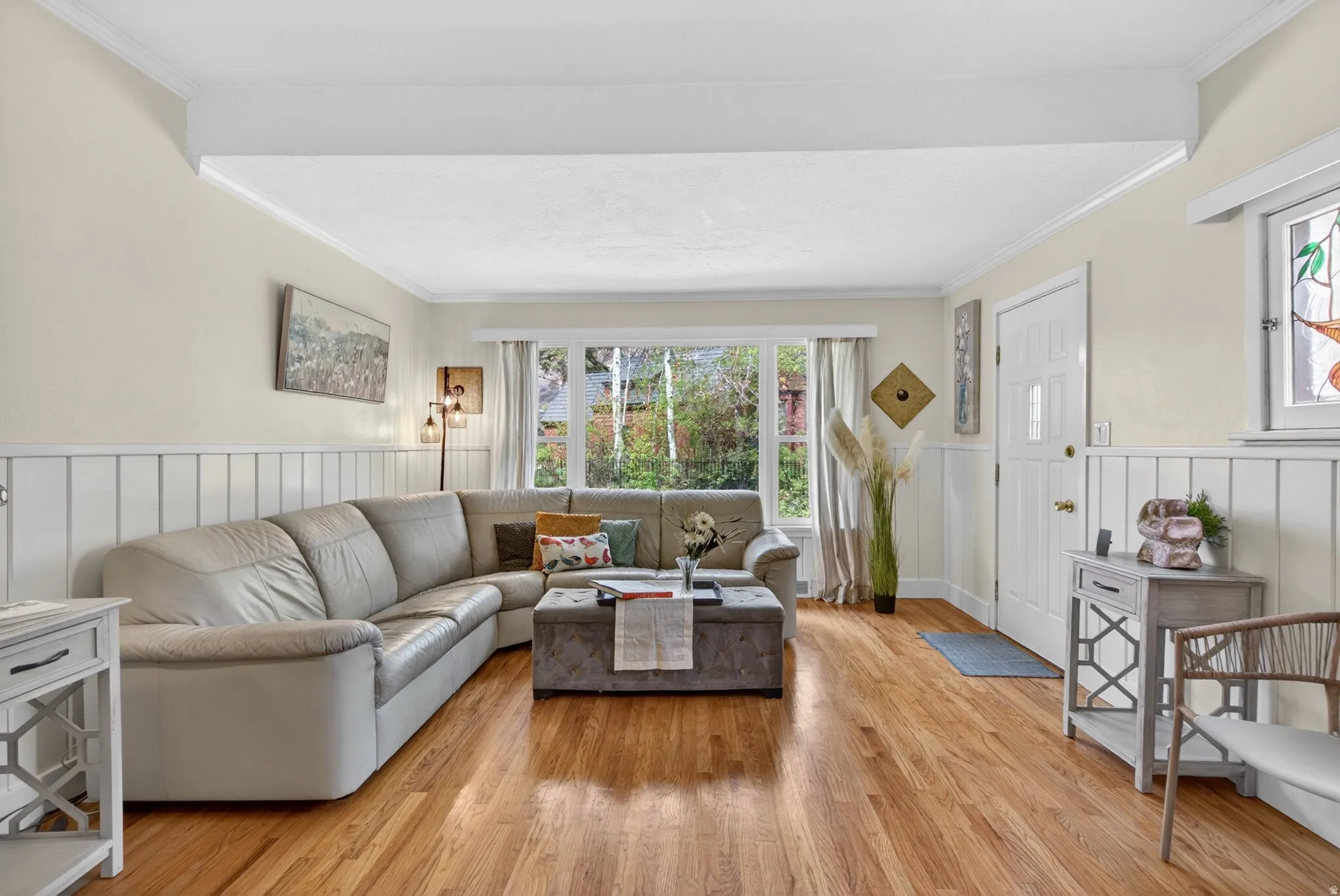 Living area with wainscoting, light wood finished floors, a decorative wall, and ornamental molding