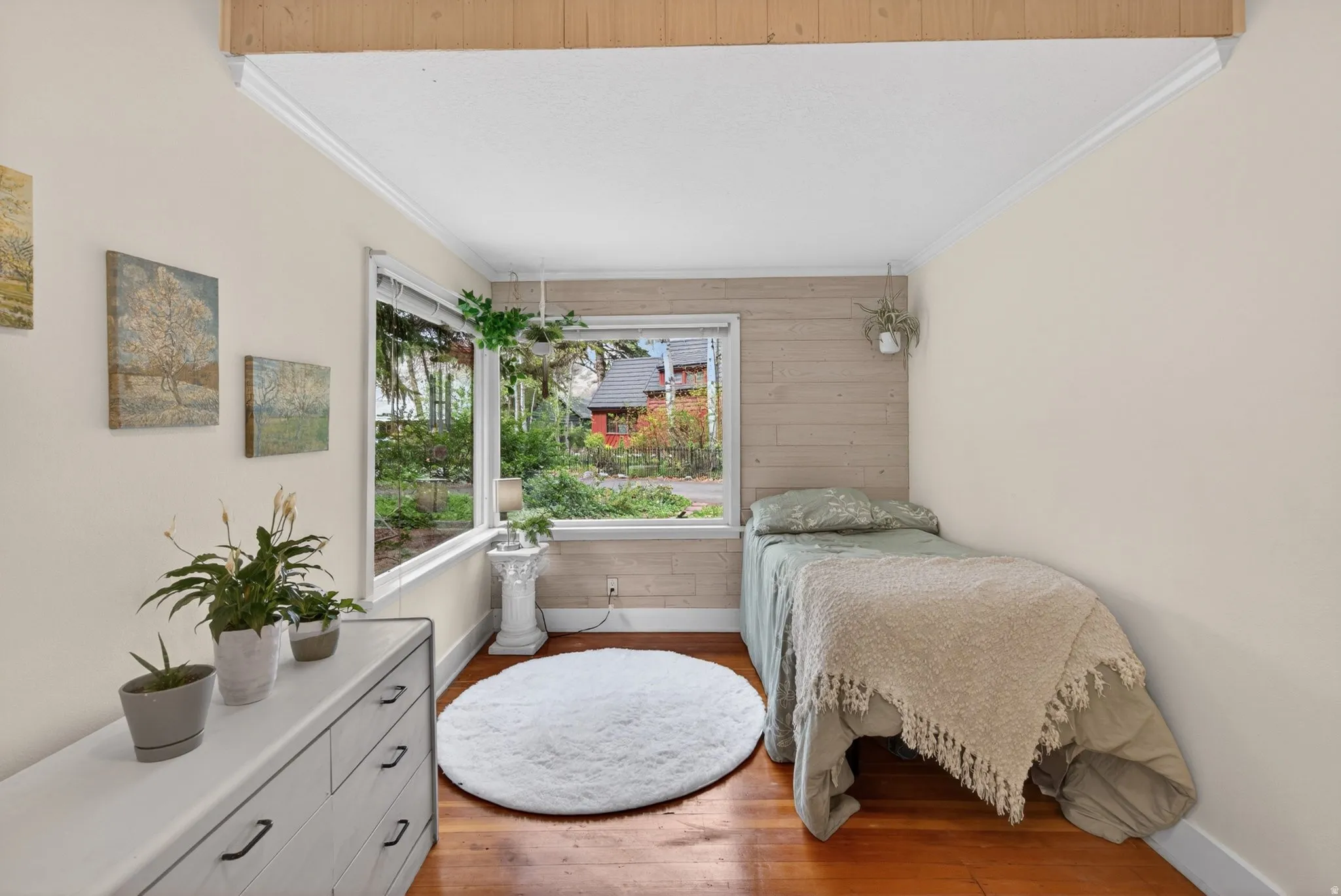 Bedroom with wooden walls, light wood-type flooring, and ornamental molding