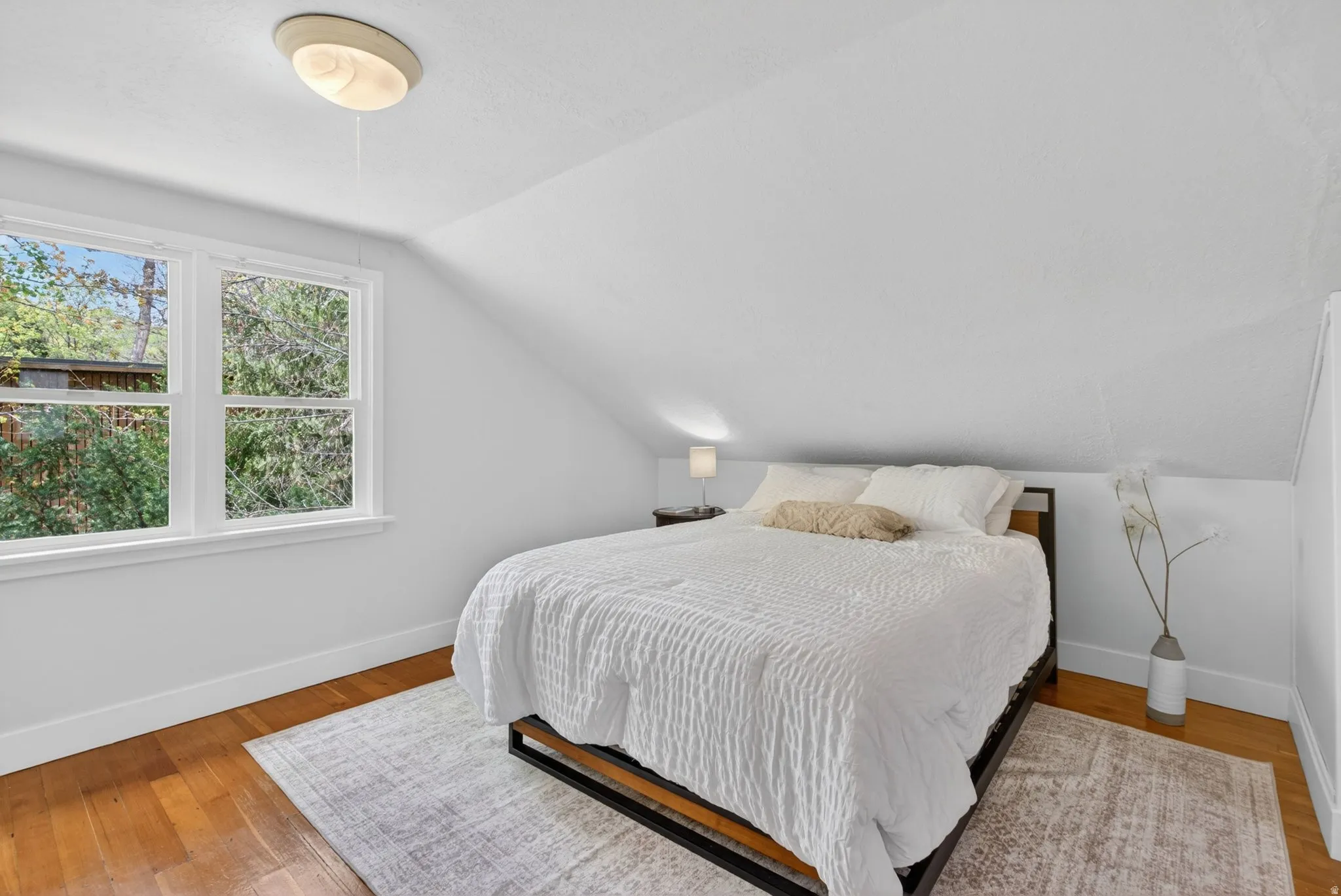 Bedroom with lofted ceiling and light wood finished floors