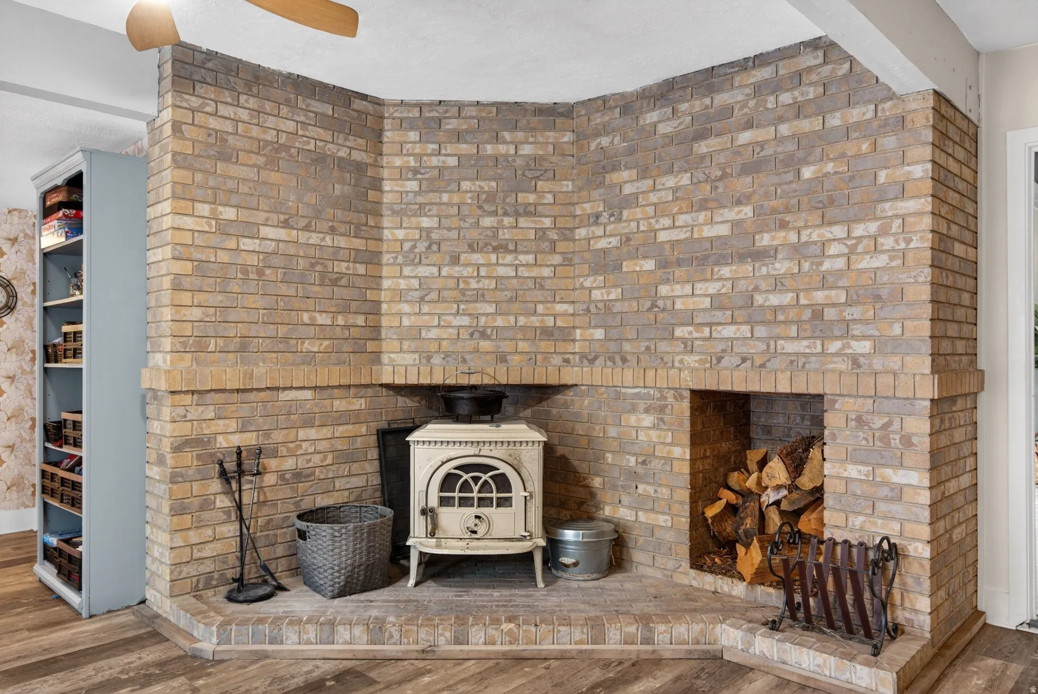 Detailed view of wood finished floors, a wood stove, and ceiling fan