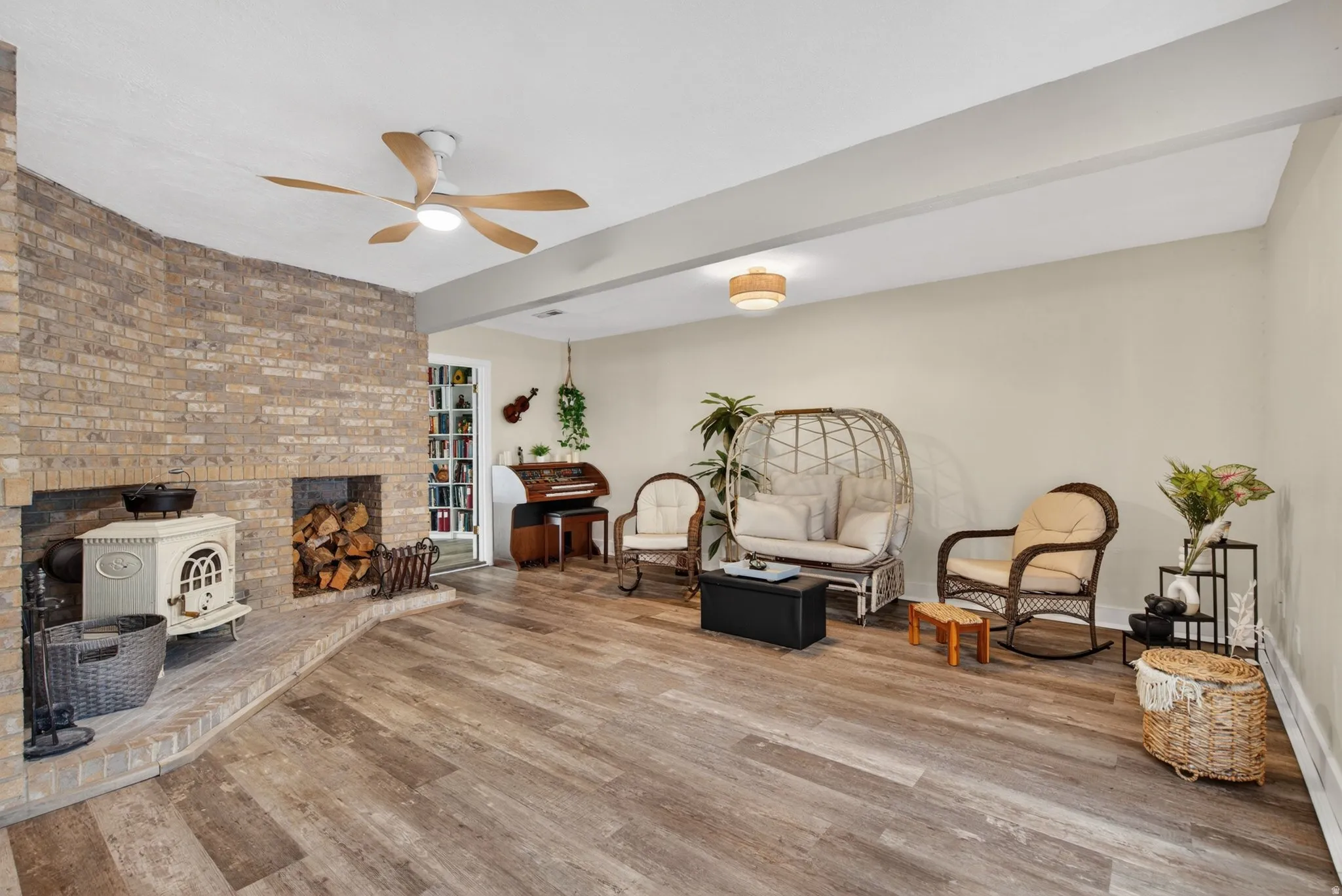 Living area featuring wood finished floors, a ceiling fan, and beam ceiling