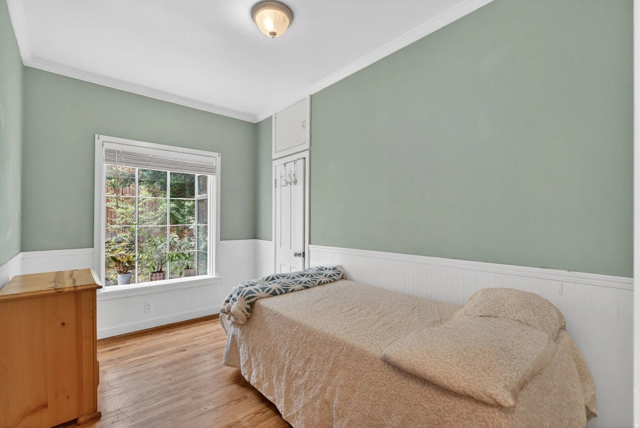 Bedroom with wainscoting, wood finished floors, and crown molding