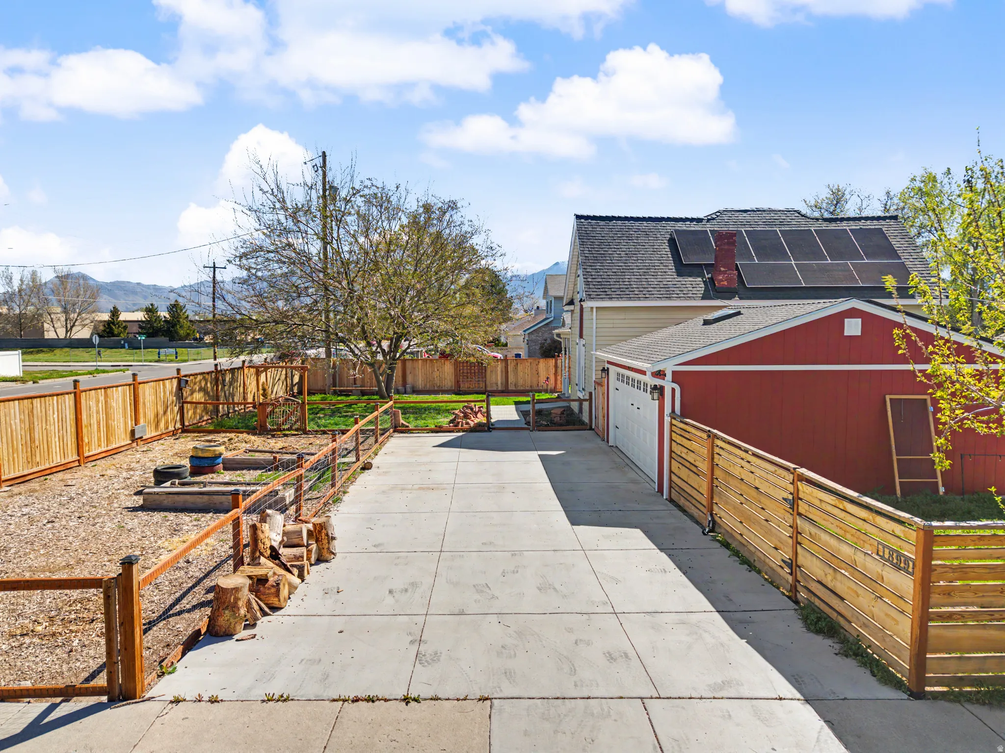 View of side of home with a garden, a fenced backyard, solar panels, a patio area, and concrete driveway