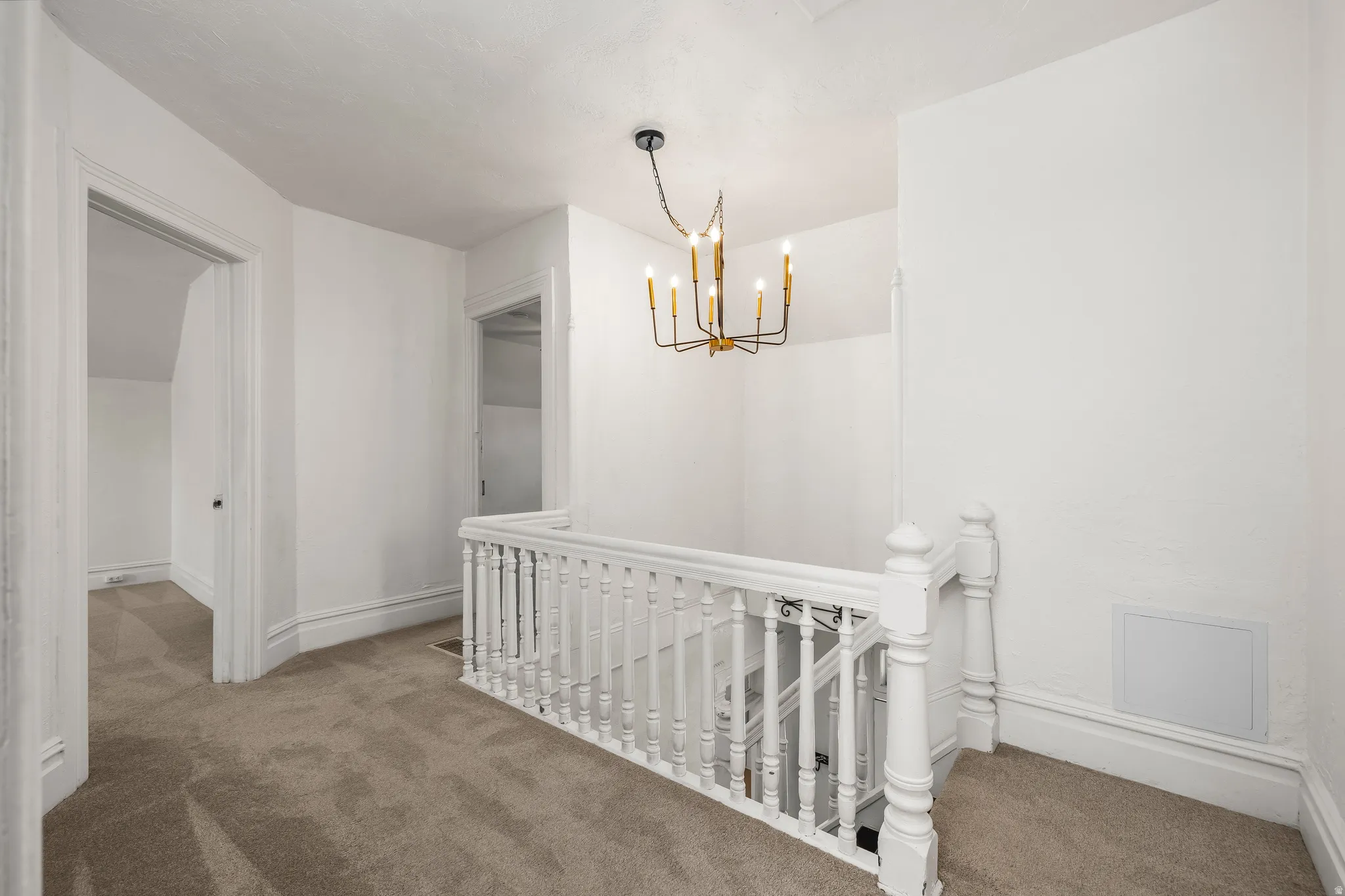 Hallway with an upstairs landing, carpet floors, and a chandelier