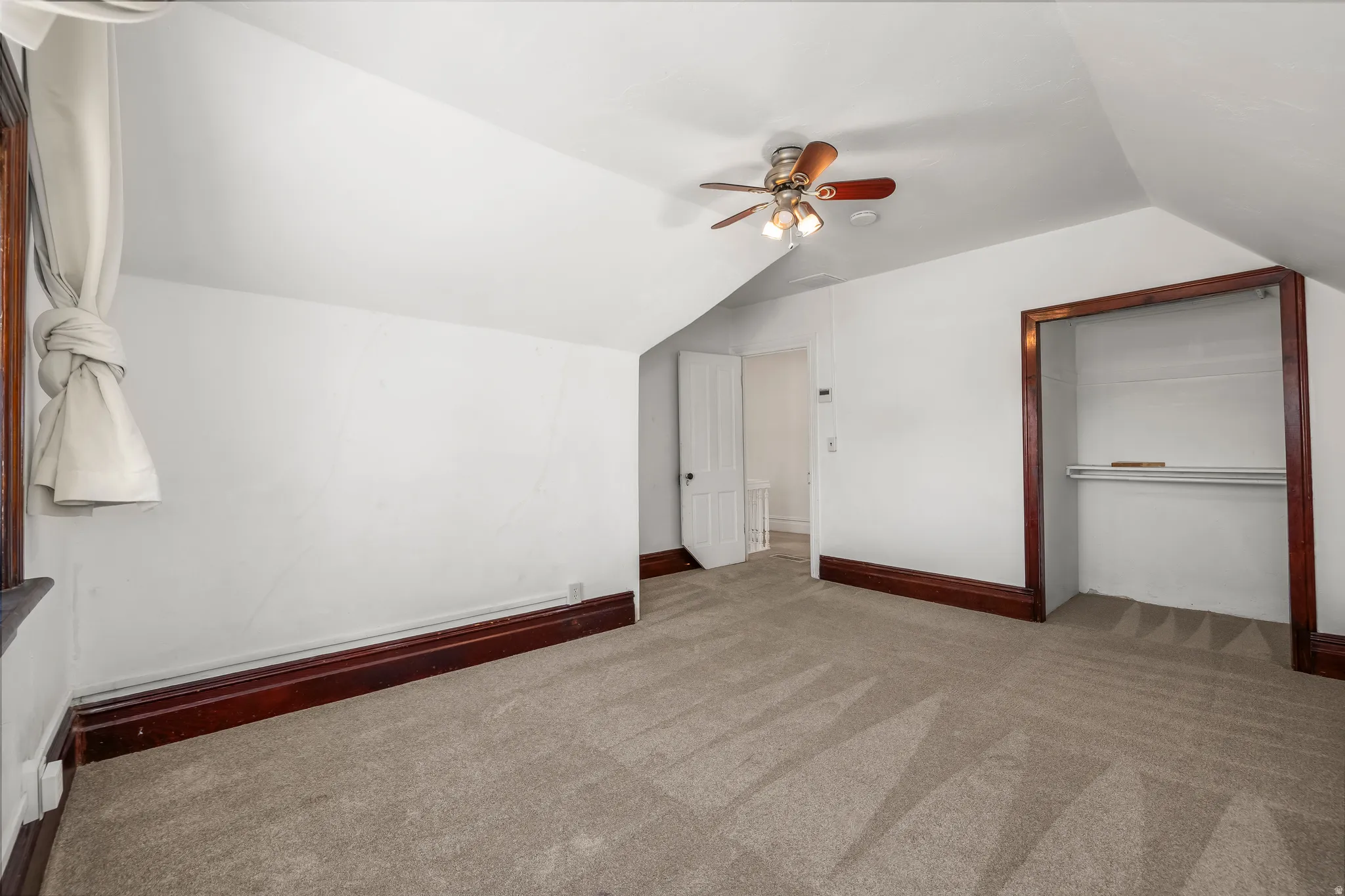 Bedroom  1 with light colored carpet, ceiling fan, and vaulted ceiling