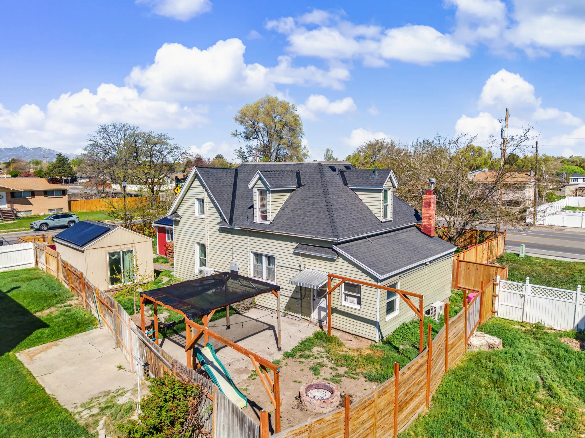Back of house featuring roof with shingles, a fenced backyard, a patio, a residential view, and an outdoor structure