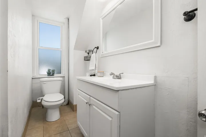 Bathroom featuring vanity, lofted ceiling, light tile patterned floors, and a textured wall