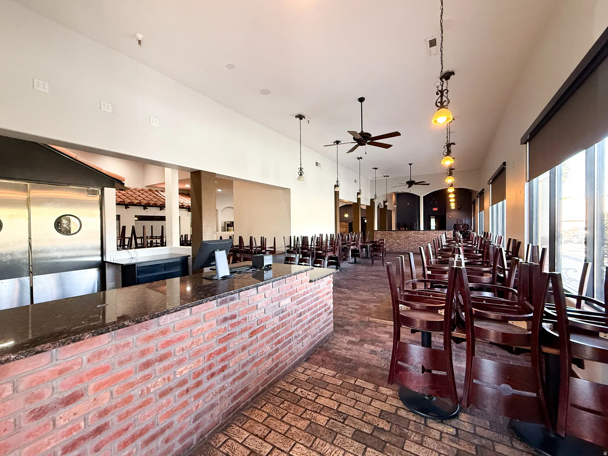Bar with ceiling fan, pendant lighting, a high ceiling, and dark stone countertops