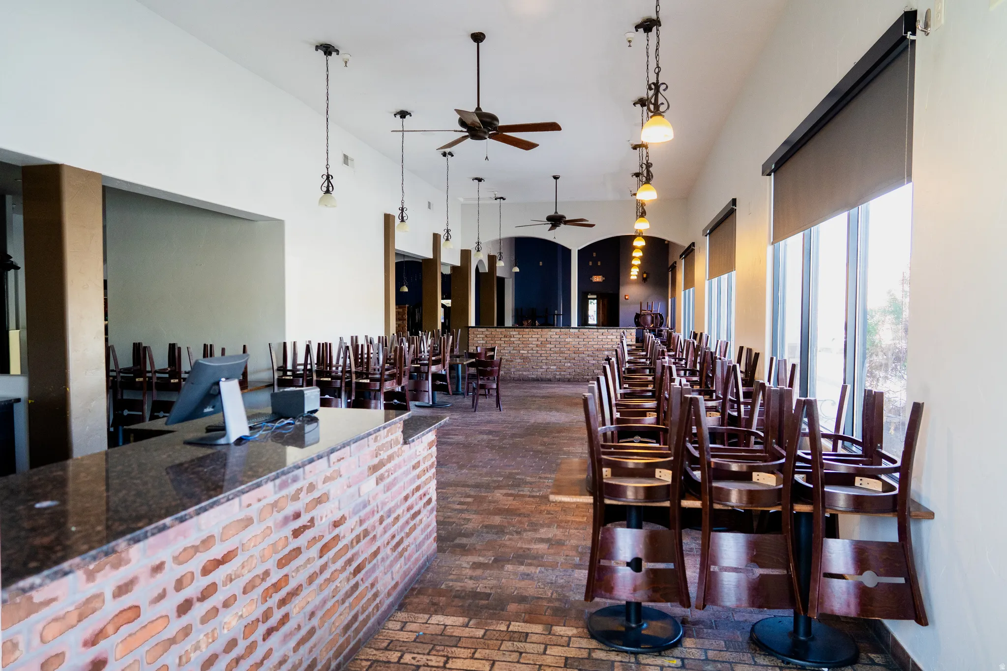 Bar with a ceiling fan, a high ceiling, pendant lighting, arched walkways, and dark stone countertops