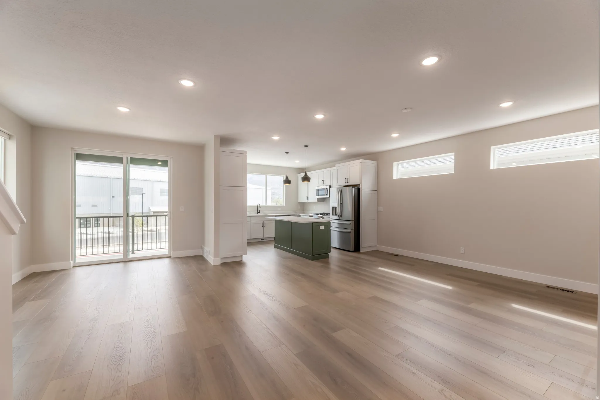 Dual tone kitchen featuring open floor plan, two tone cabinets, stainless steel appliances, light wood-style flooring, and light countertops