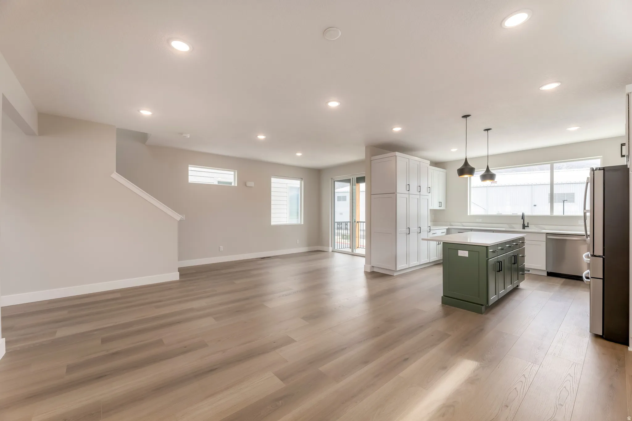Dual tone kitchen featuring stainless steel appliances, open floor plan, plenty of natural light, light wood-type flooring, and dual tone cabinetry