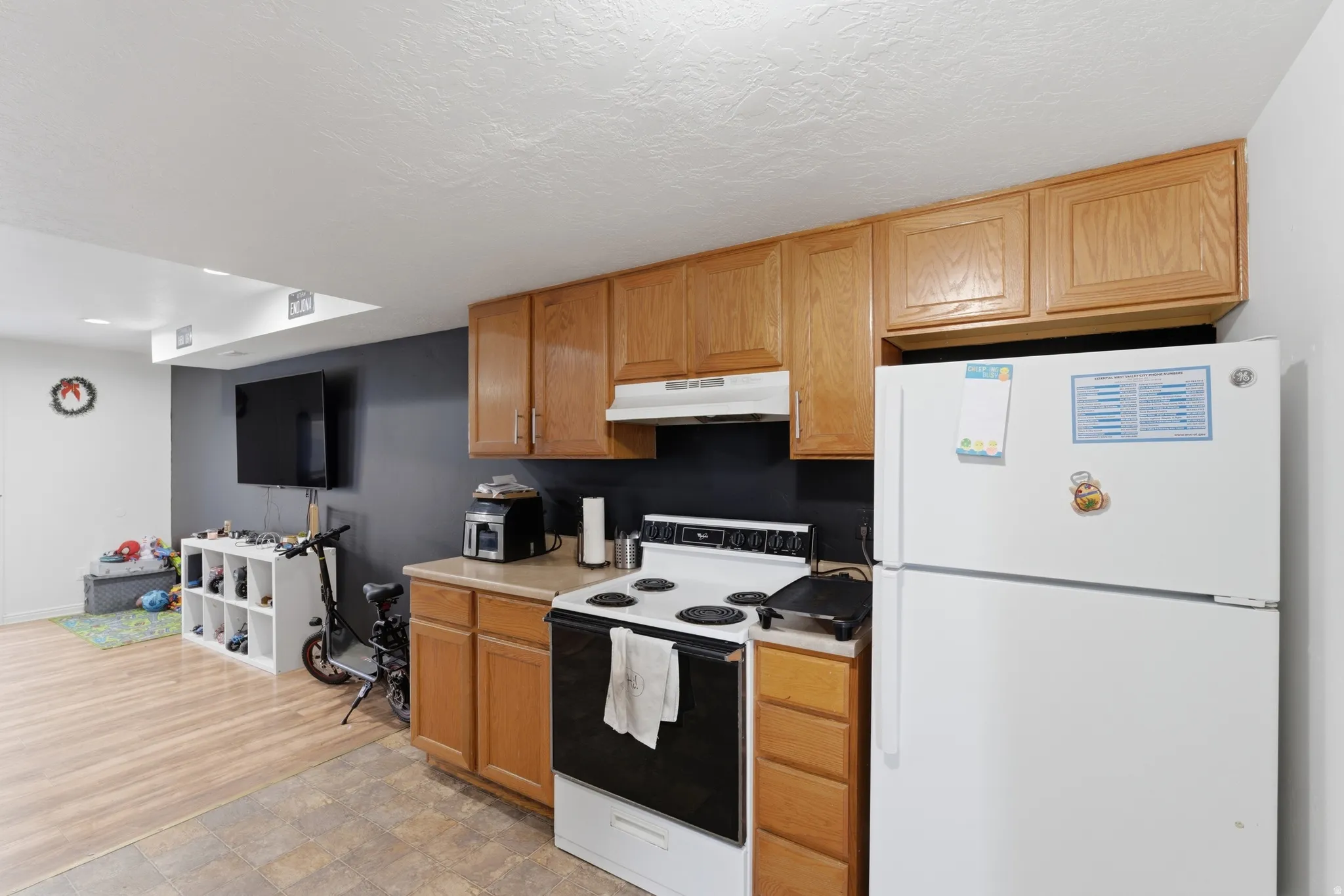 Kitchen featuring light countertops, white appliances, and wood finish cabinetry
