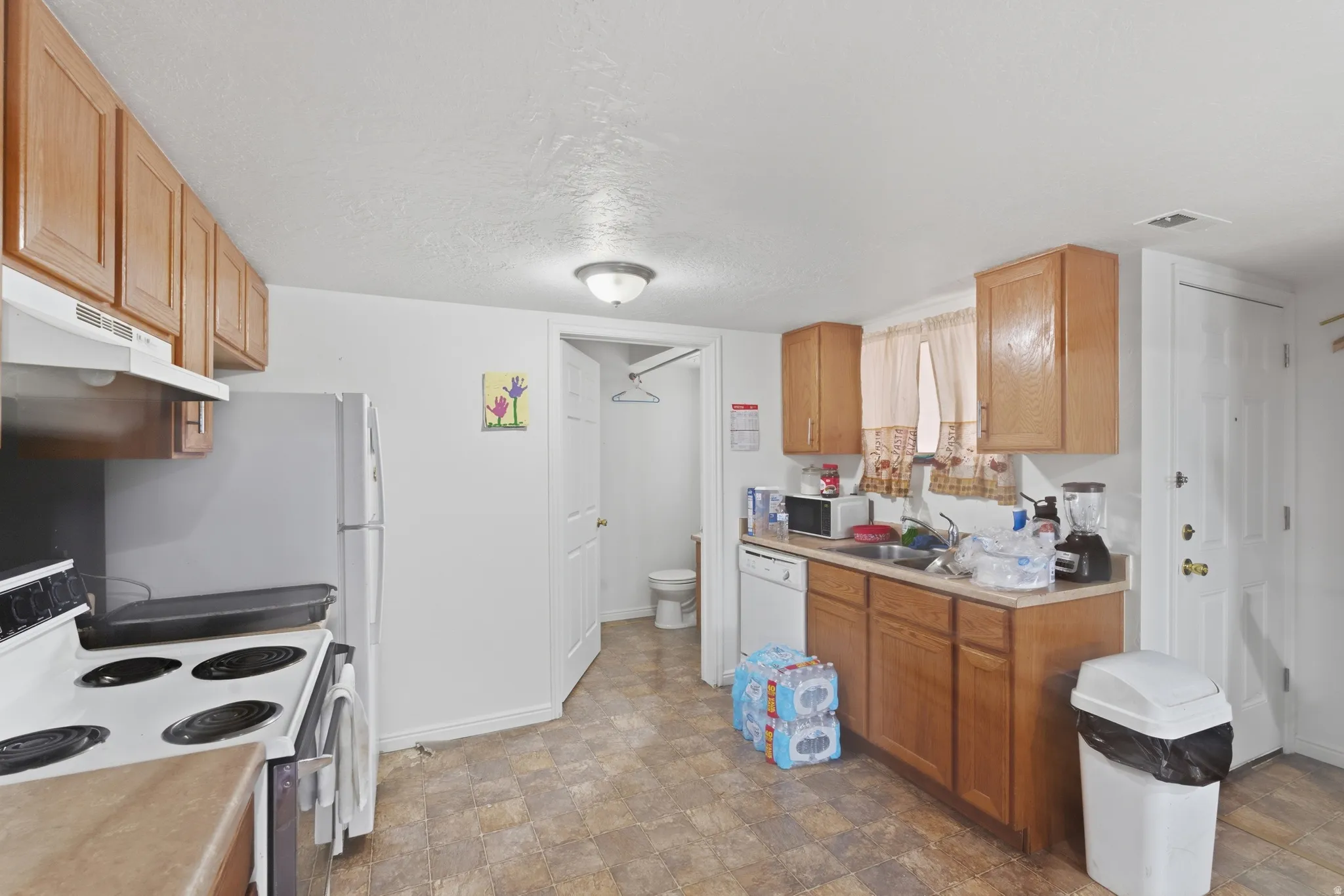 Kitchen featuring white appliances, stone finish floors, light countertops, and a textured ceiling