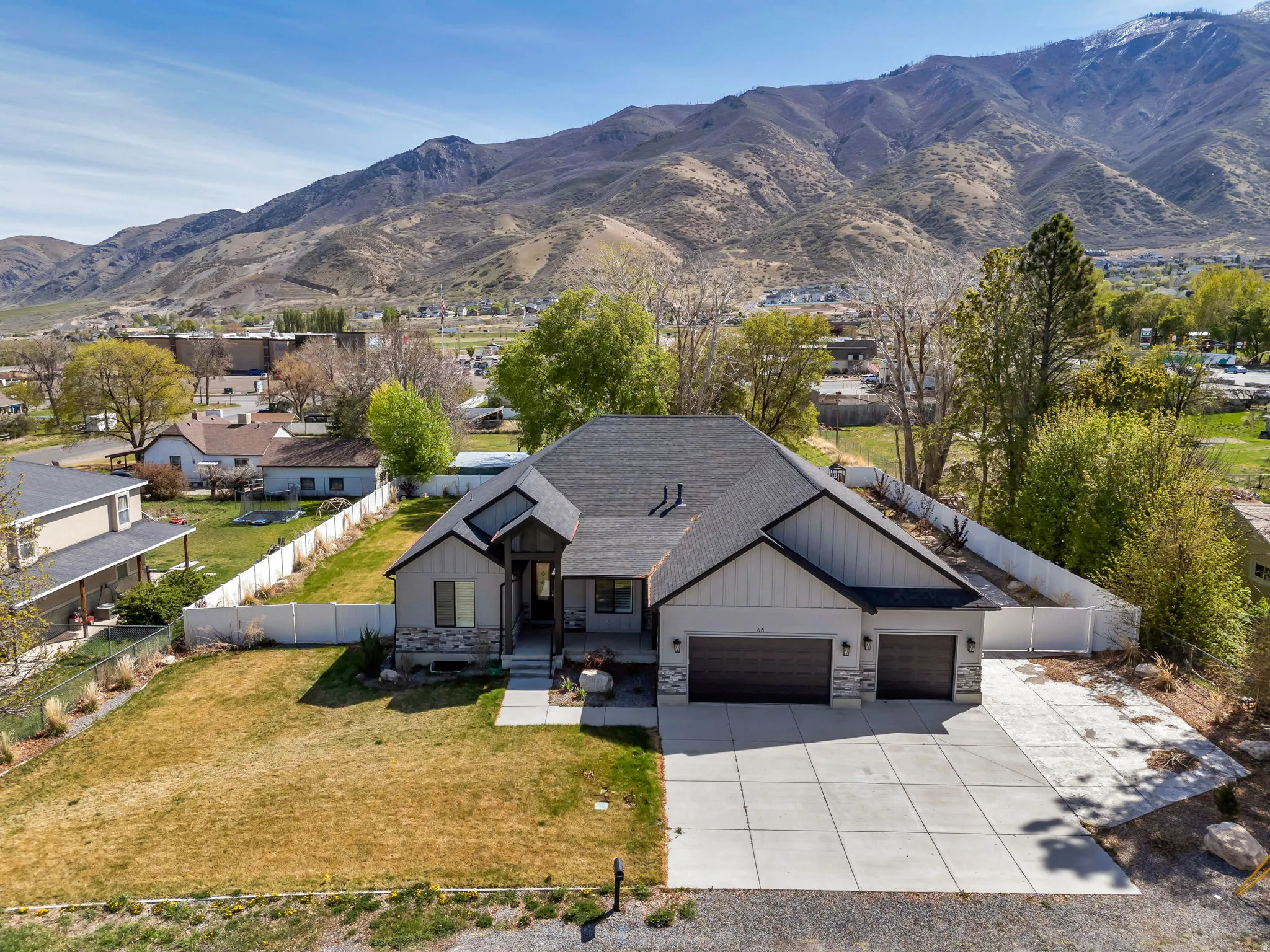 Modern inspired farmhouse featuring stone siding, an attached garage, a mountain view, concrete driveway, and board and batten siding