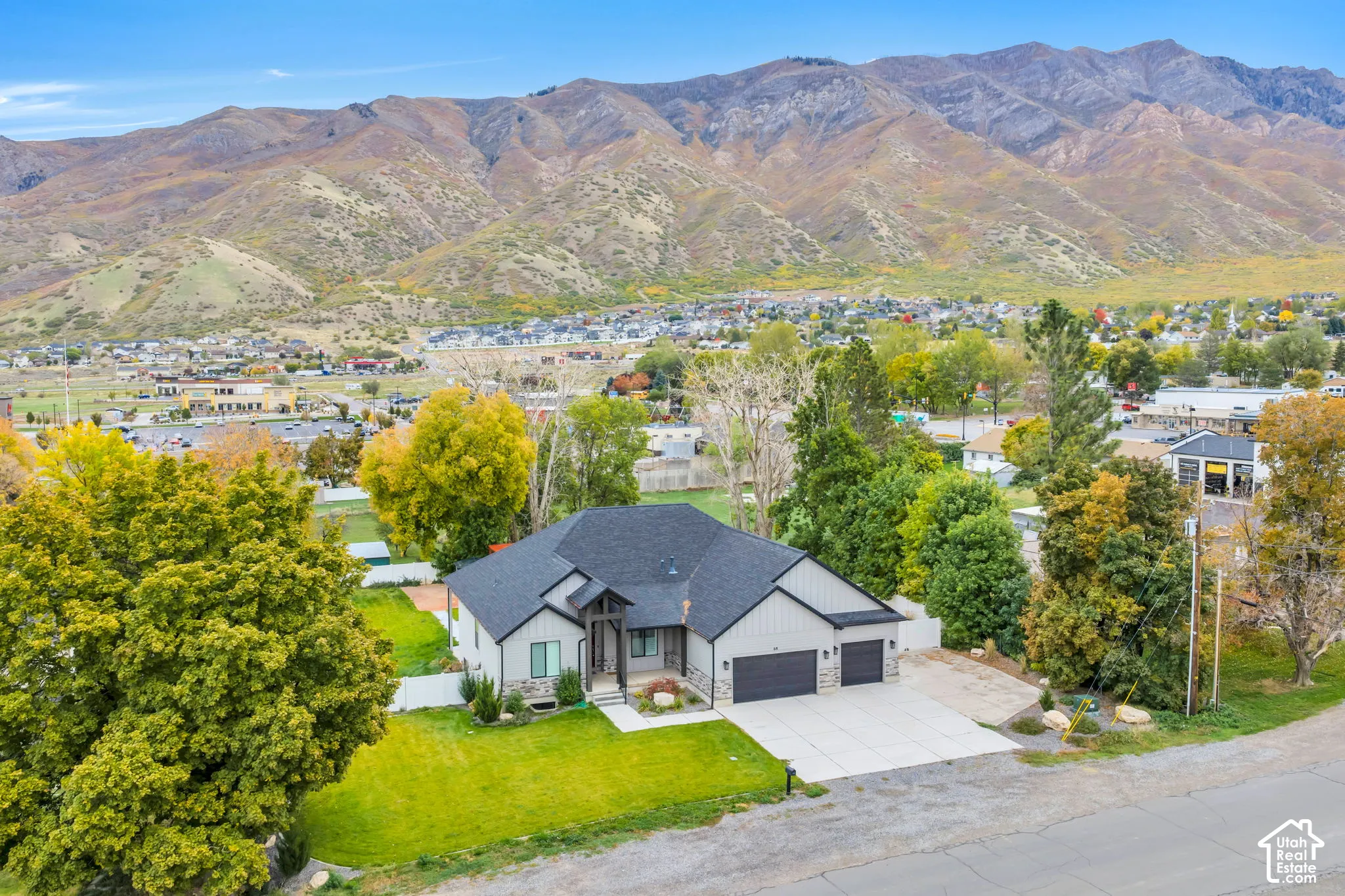 Single-level residence featuring a multi-gabled roofline, stone and siding exterior, attached three-car garage, and expansive mountain backdrop