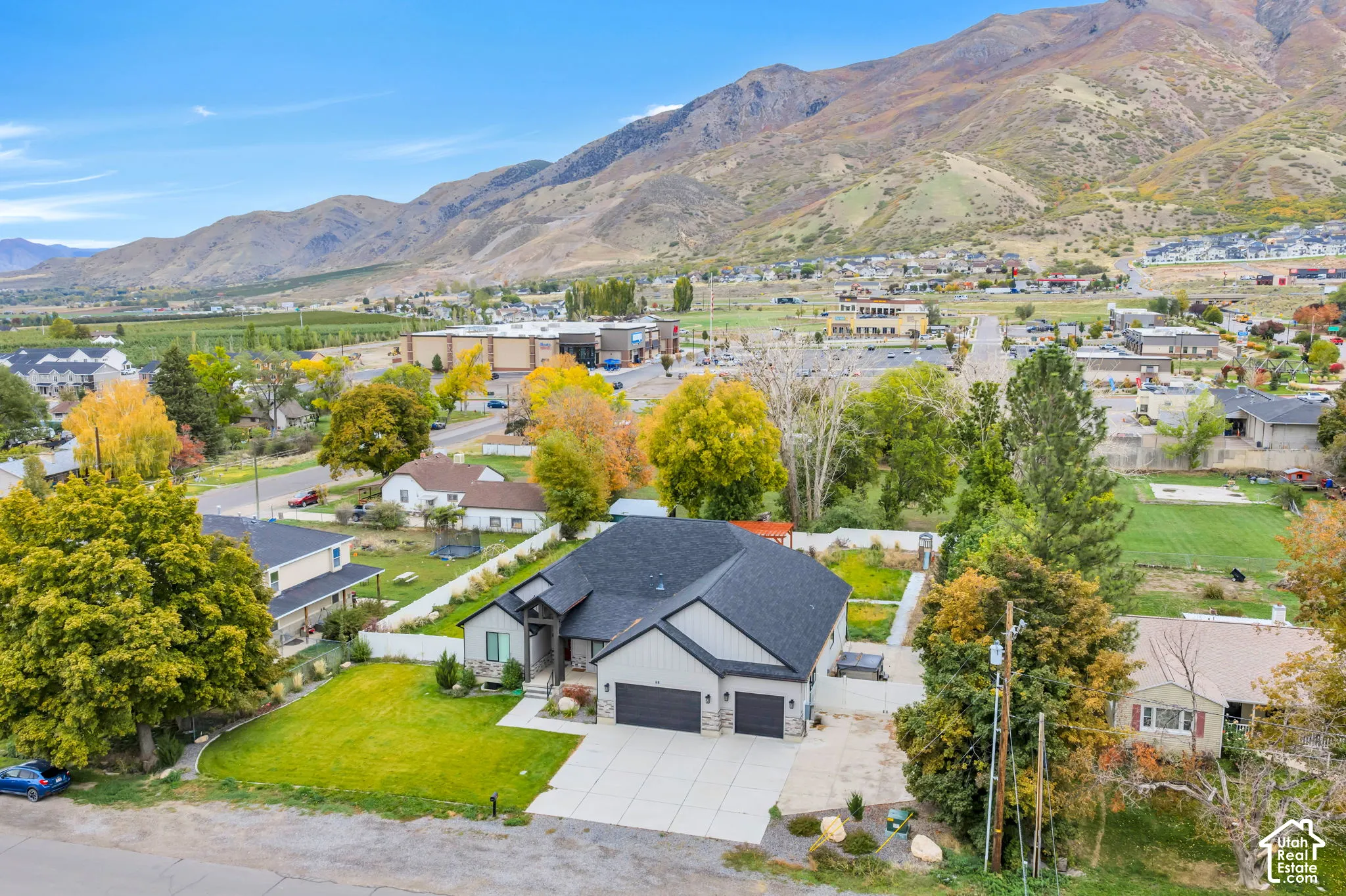 Single-story residence featuring a multi-gabled asphalt shingle roof, stone and siding exterior, attached three-car garage, and concrete driveway, all set against a mountainous backdrop