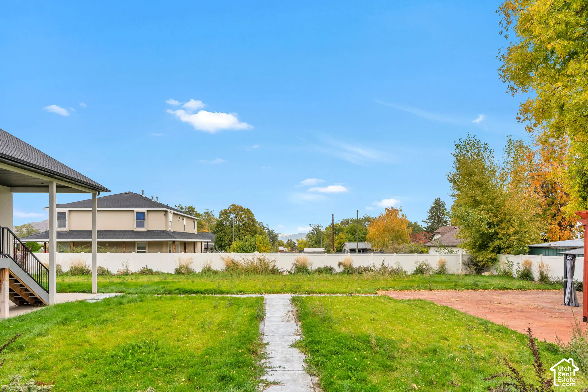 Expansive backyard featuring a concrete patio, a stone paver walkway, and a perimeter vinyl privacy fence