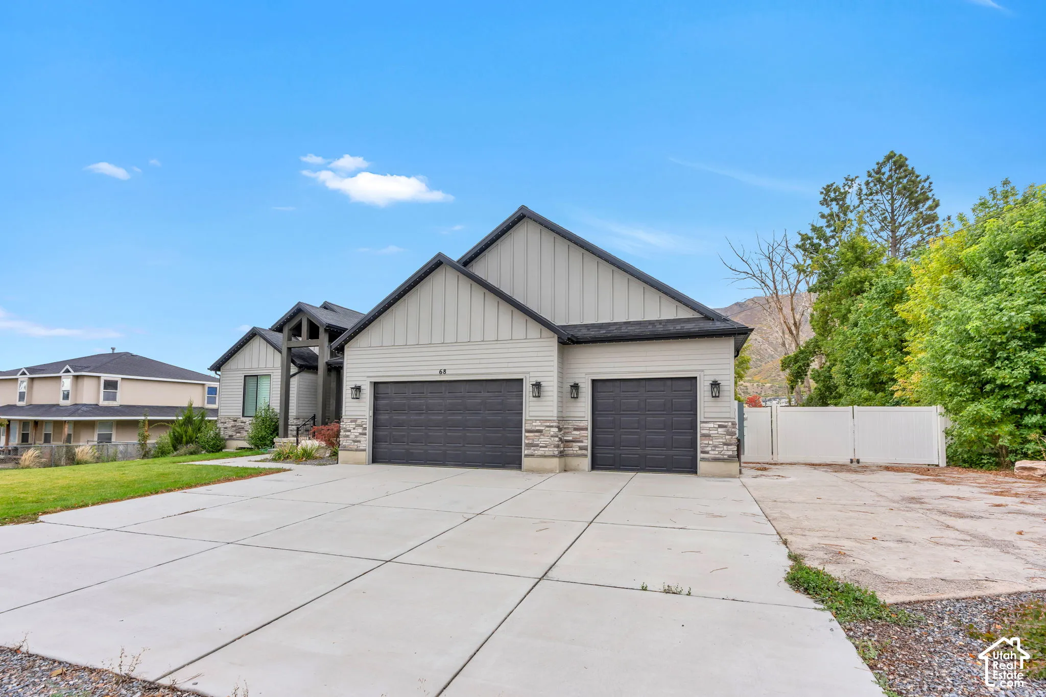 Exterior featuring multi-textured siding, stacked stone accents, a three-car garage, and a concrete driveway with supplemental side parking