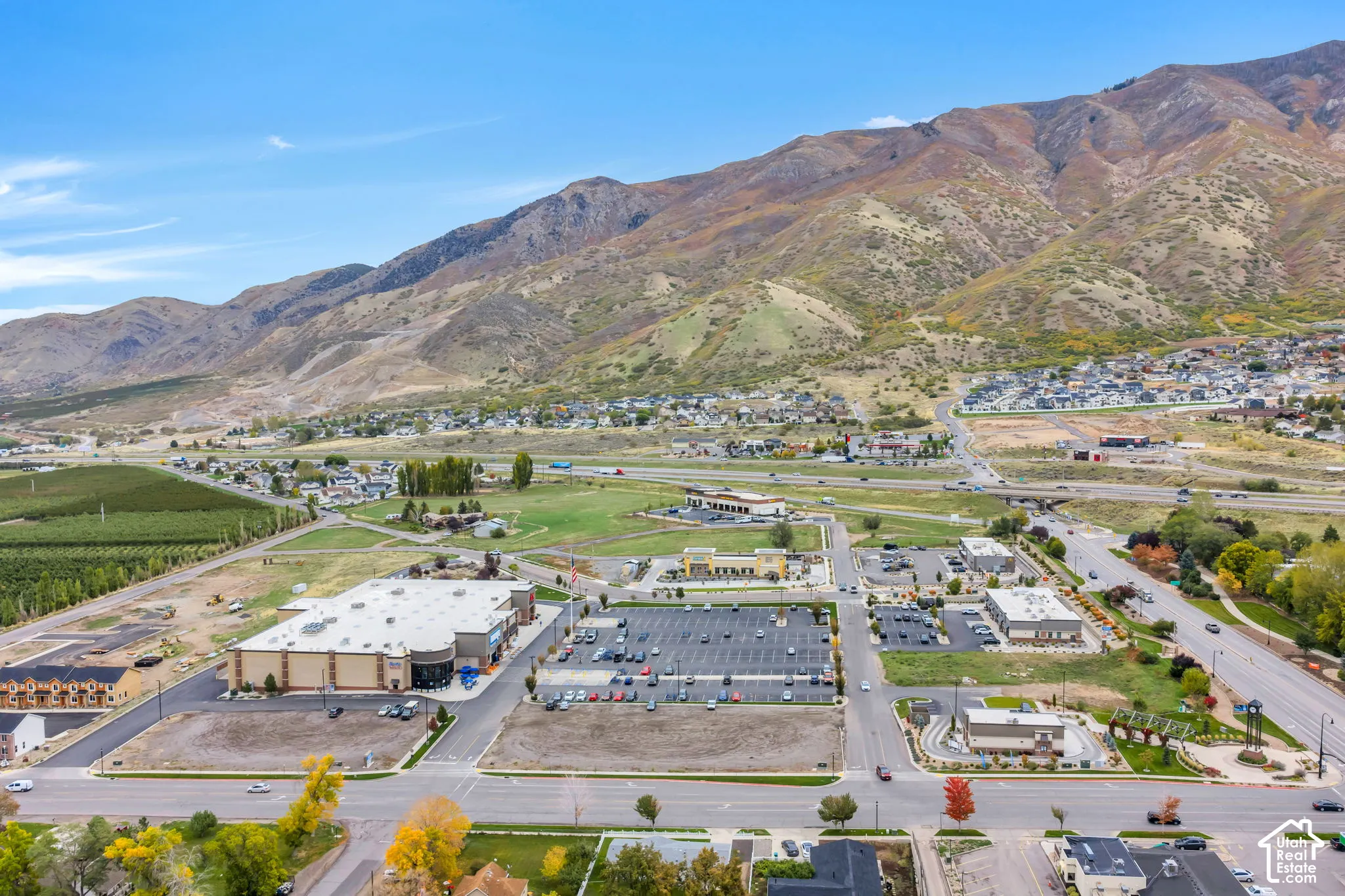 Aerial perspective featuring a prominent mountain backdrop, paved commercial parking areas, and established regional road infrastructure