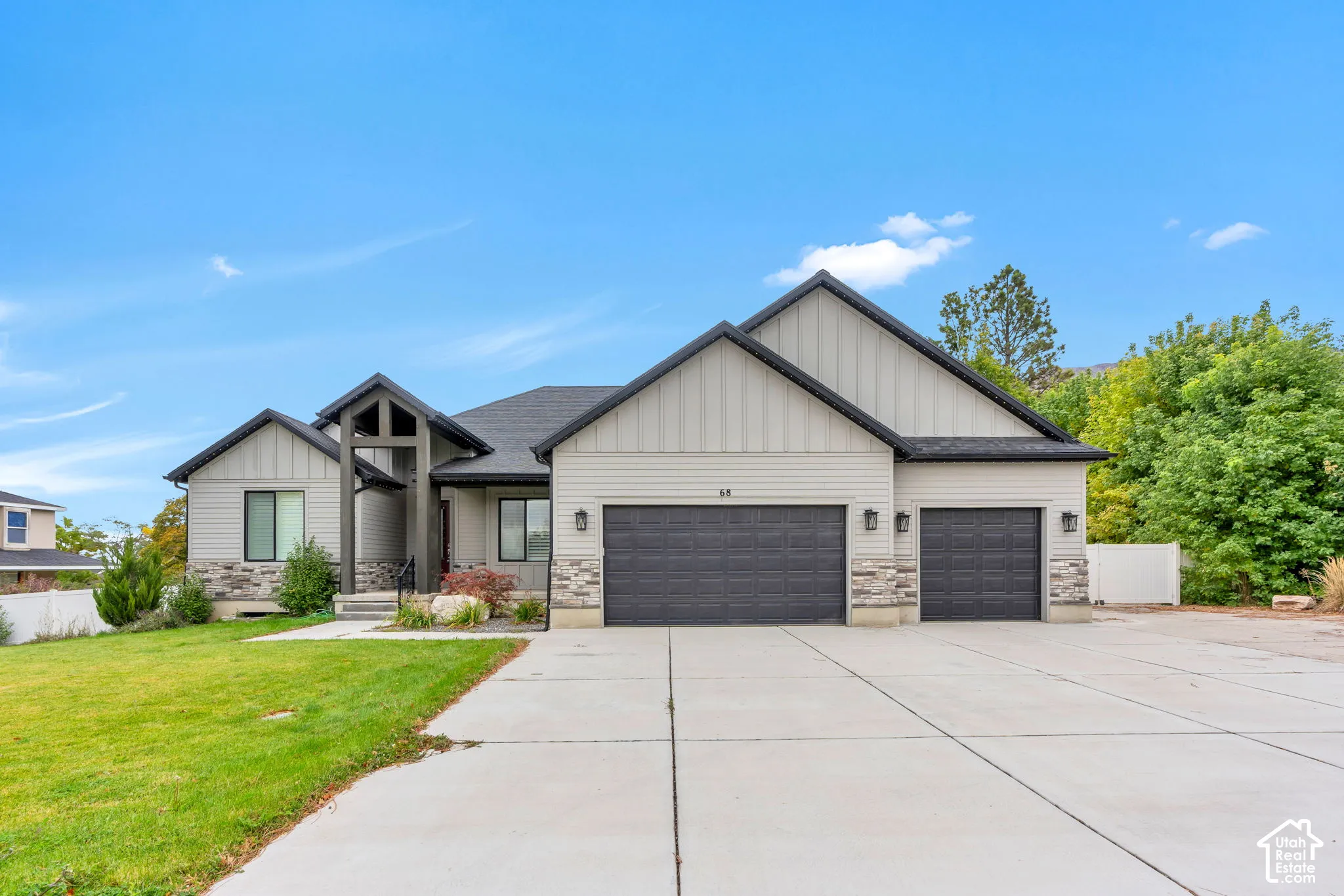Single-story residence featuring horizontal and vertical siding, a stone veneer foundation, three-car garage, and a covered front entryway with timber-style accents